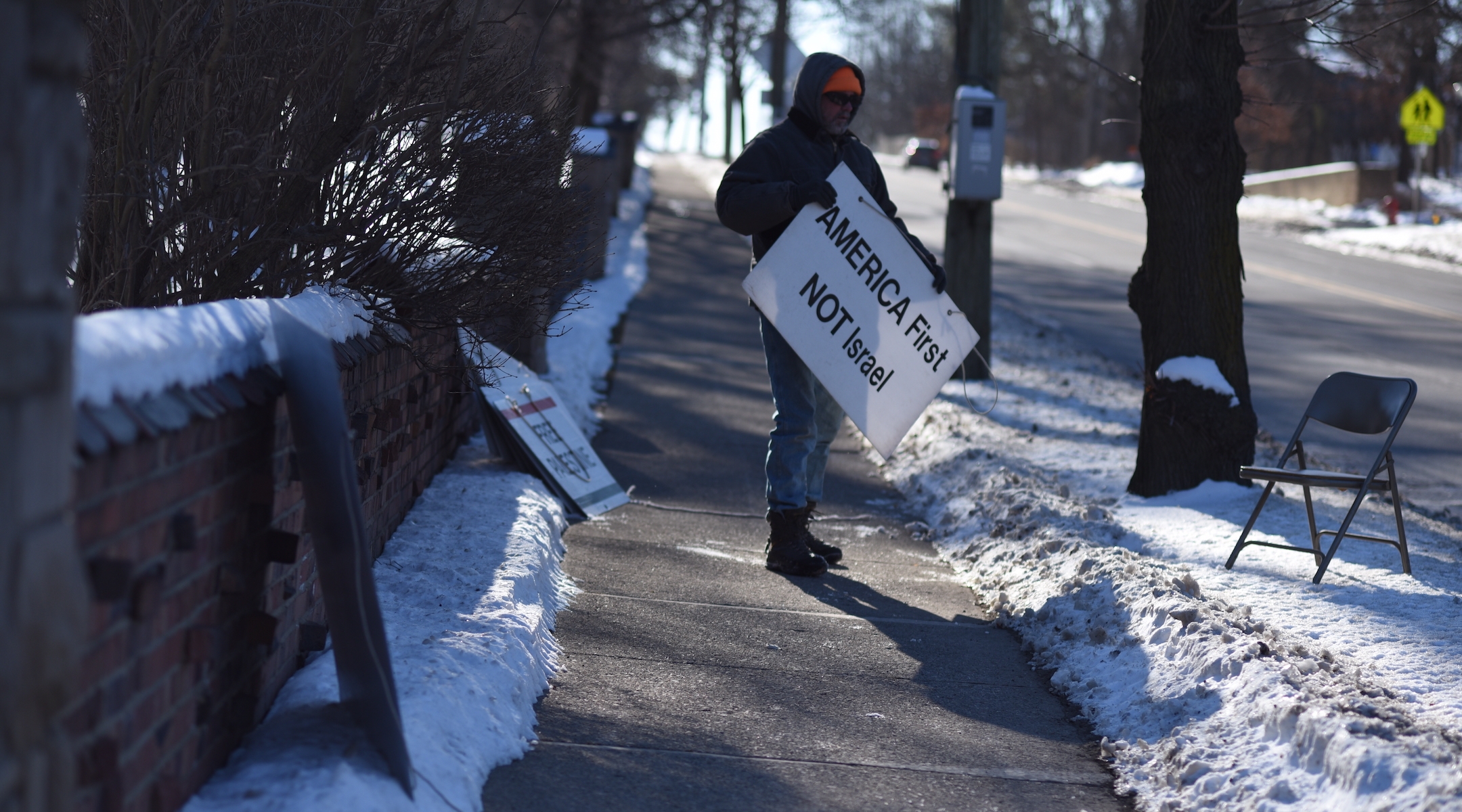 A protester stands outside Beth Israel Congregation in Ann Arbor, Michigan, flanked by anti-Israel and antisemitic signs, in 2020. On Jan. 18, 2022, the Ann Arbor City Council formally condemned the weekly protests, which had been going on for 18 years. (Alex Sherman/Jewish Telegraphic Agency)