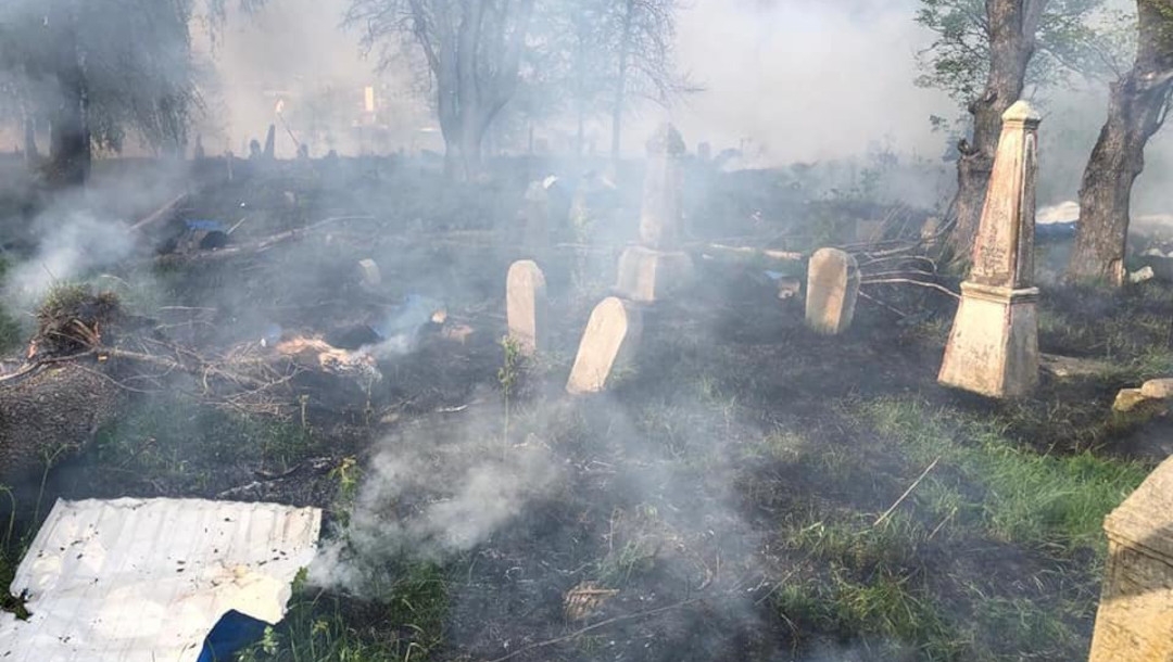 Smoke billows among headstones of a Jewish cemetery that reportedly was bombed in Hulkhiv, Ukraine, May 8, 2022. (Dmitry Zhivitsky / Facebook)