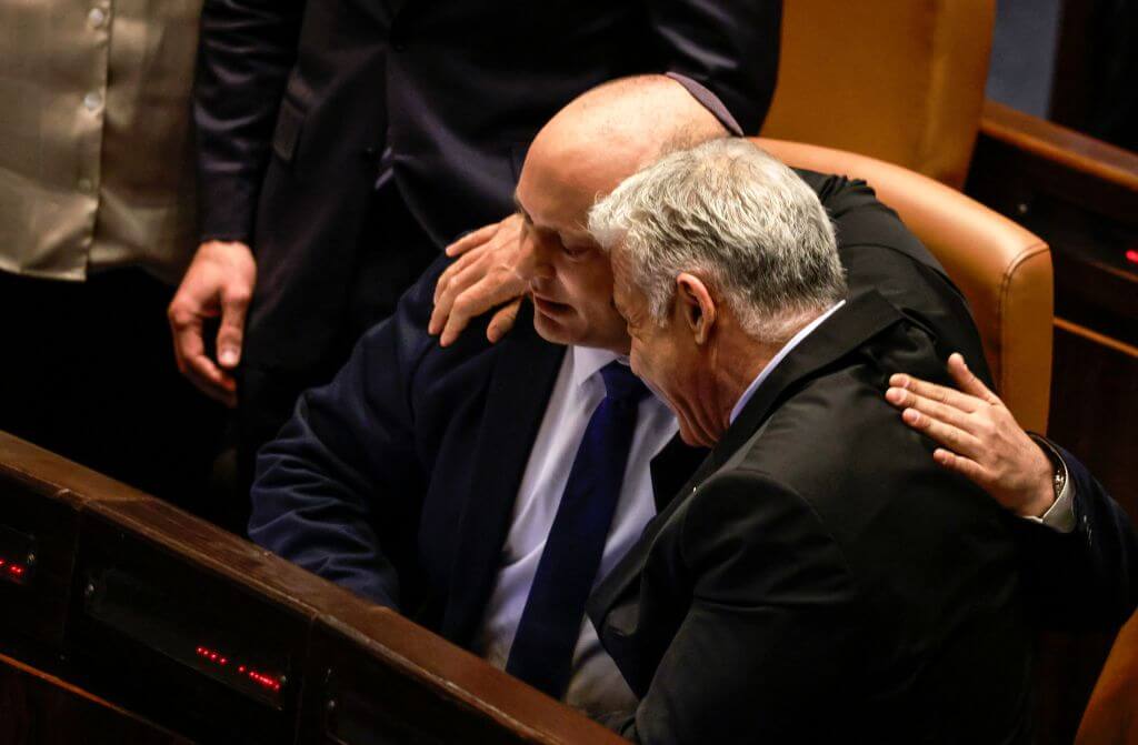 Israeli Minister of Foreign Affairs Yair Lapid (R) and outgoing Prime Minister Naftali Bennett, embrace each other at the Knesset (parliament), following the dissolution of the parliament, in Jerusalem on June 30, 2022.