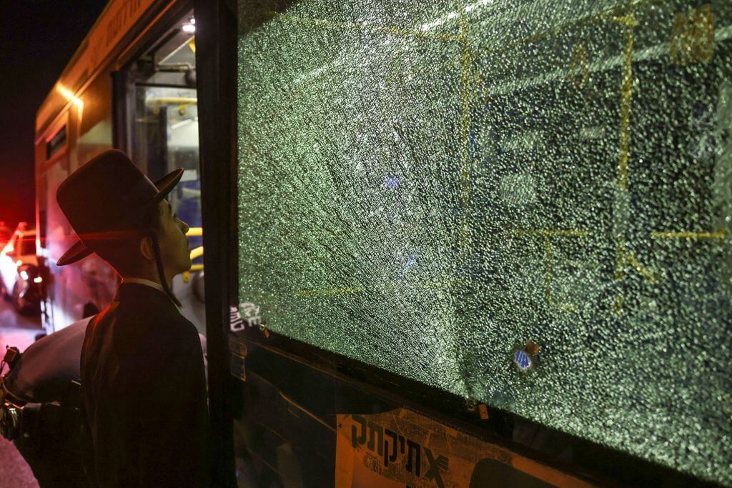 An ultra-Orthodox Jewish man looks at a bullet impact on a bus window after an attack outside Jerusalem's Old City, August 14, 2022. 