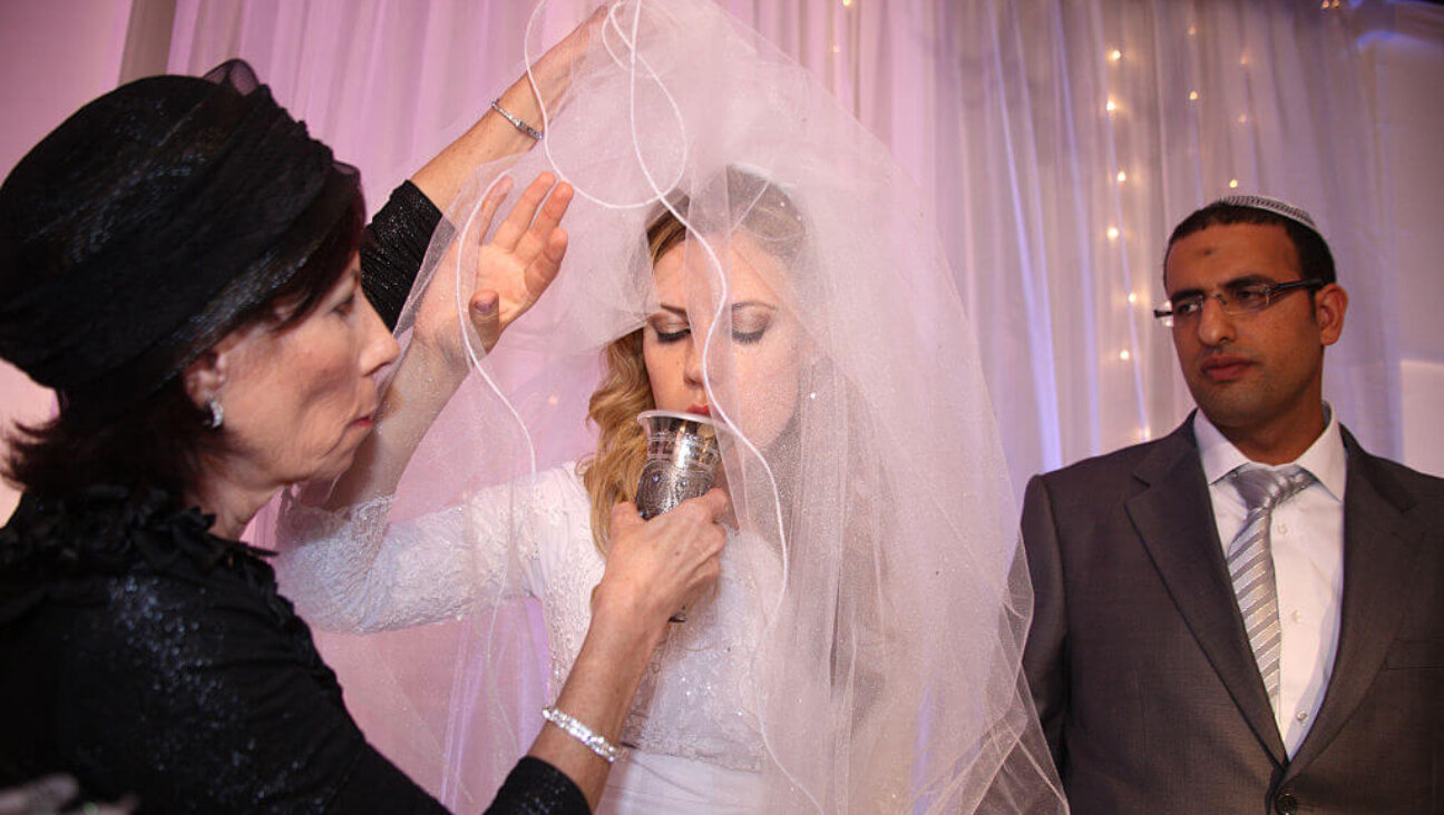 Under the Chuppah (or canopy) at an Orthodox Jewish wedding, the bride drinks wine from a cup held by her mother as her groom watches, Ness Tziona, Israel, June 9, 2010. 