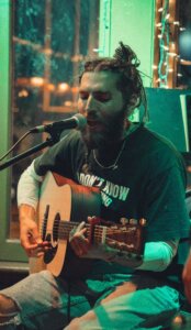 A singer playing the guitar in green lighting