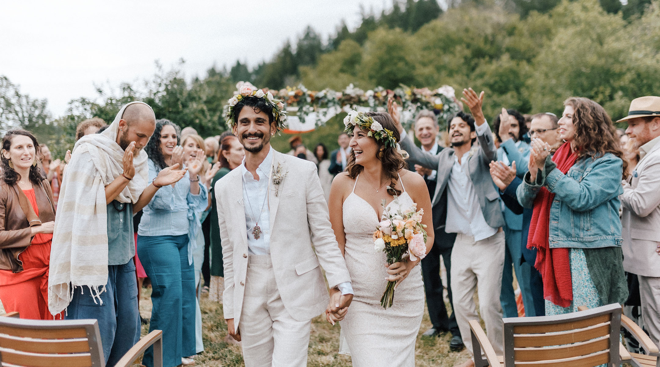 The bride and groom, Ophir Haberer and Adi Aboody, exit the chuppah after the ceremony with family and friends applauding. (Luna Munn Photography)