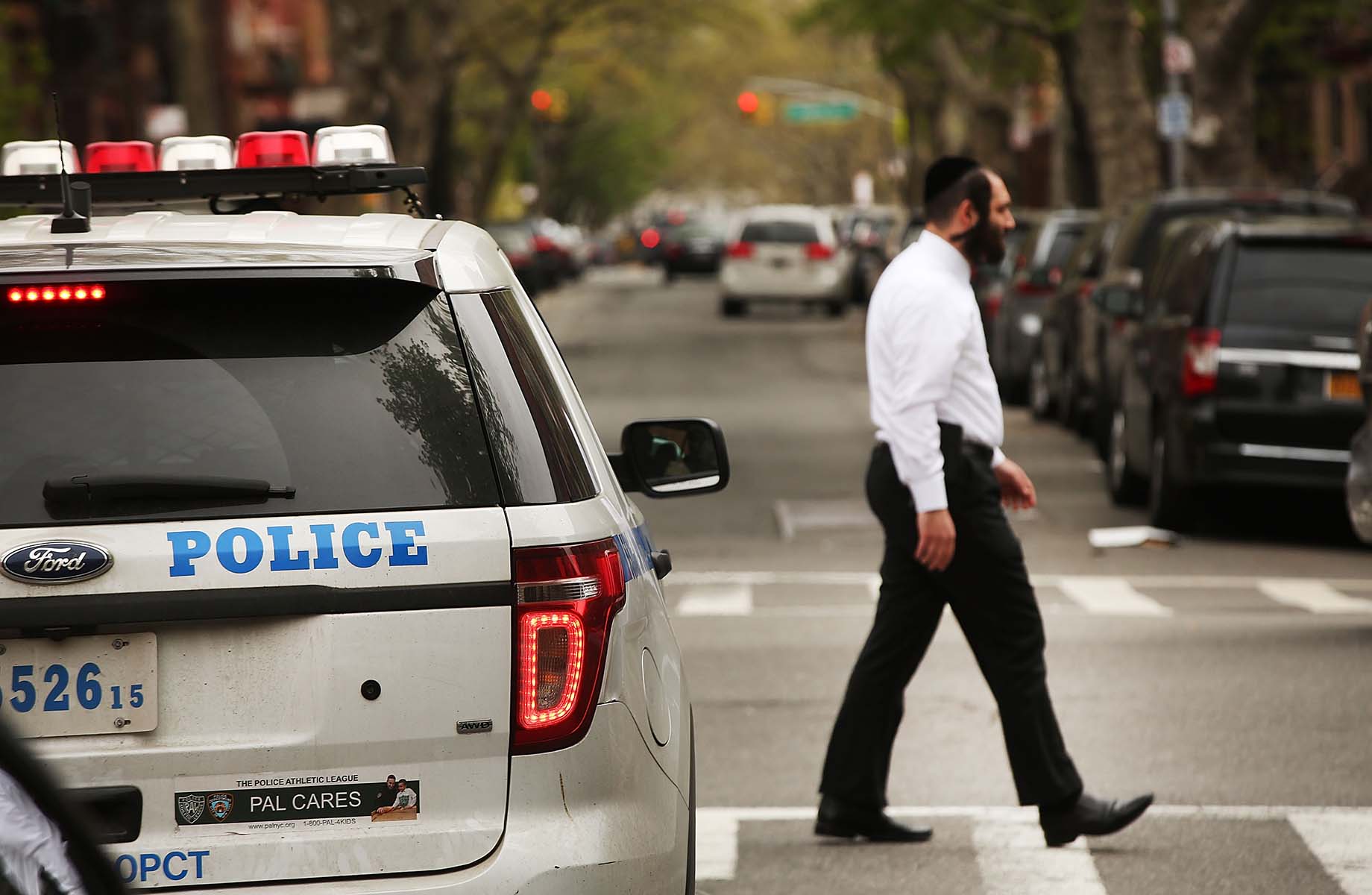 A Hasidic man walks by a police car in a Jewish Orthodox neighborhood in Brooklyn, April 24, 2017. (Spencer Platt/Getty Images)