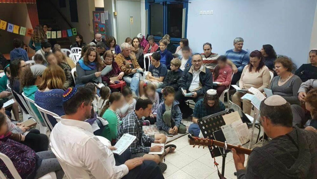 The Yuval congregation prays together inside a cramped school classroom. 