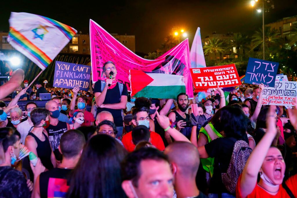 Participants hold a Palestinian flag and placards as they take part in Tel Aviv's annual Pride Parade amid the COVID-19 pandemic, on June 28, 2020.