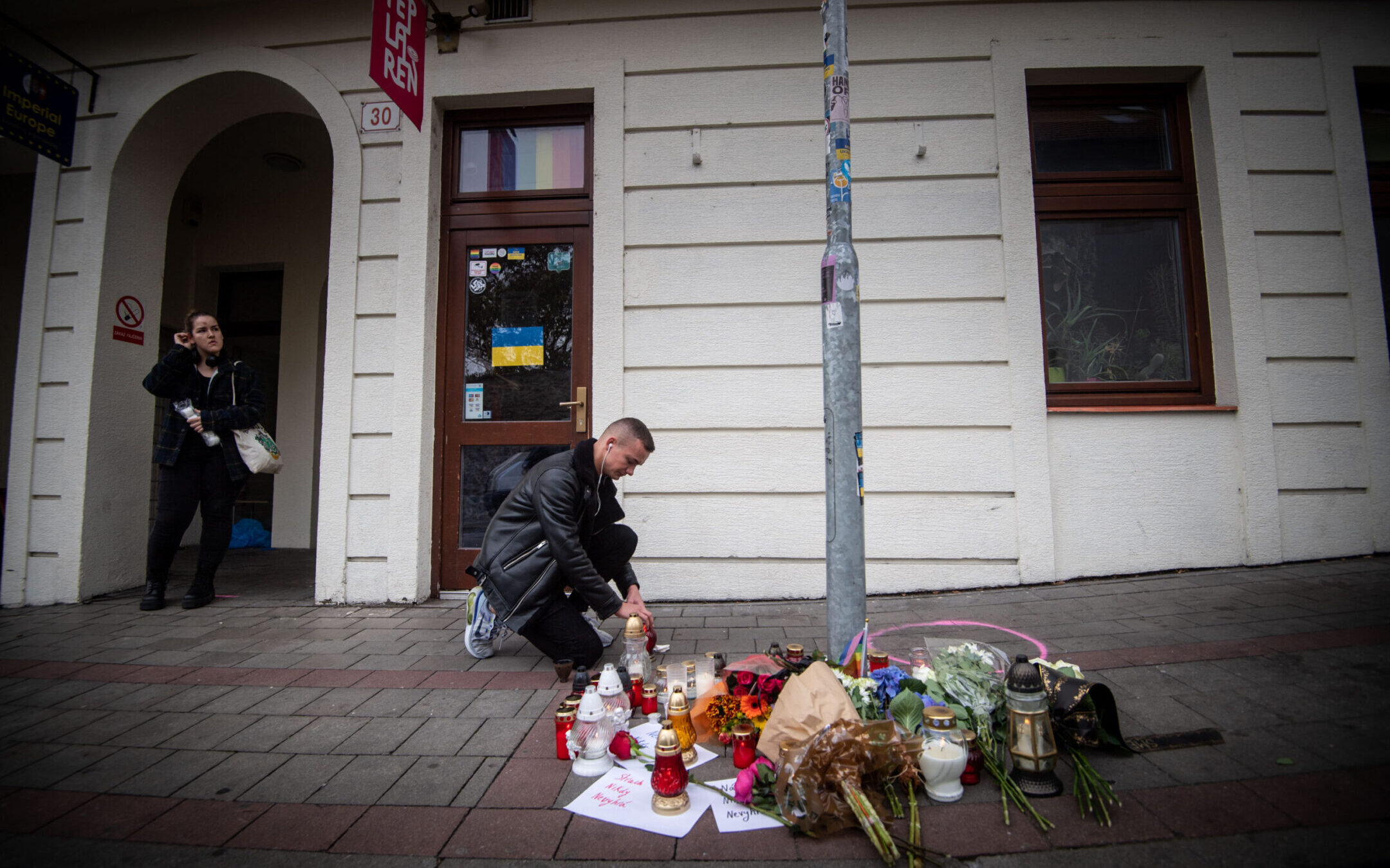 A man places a candle on the pavement at Zamocka Street in Bratislava after a “radicalized teenager” murdered two men there, Oct. 13. 2022 (Photo by Vladimir Simicek/AFP via Getty Images)