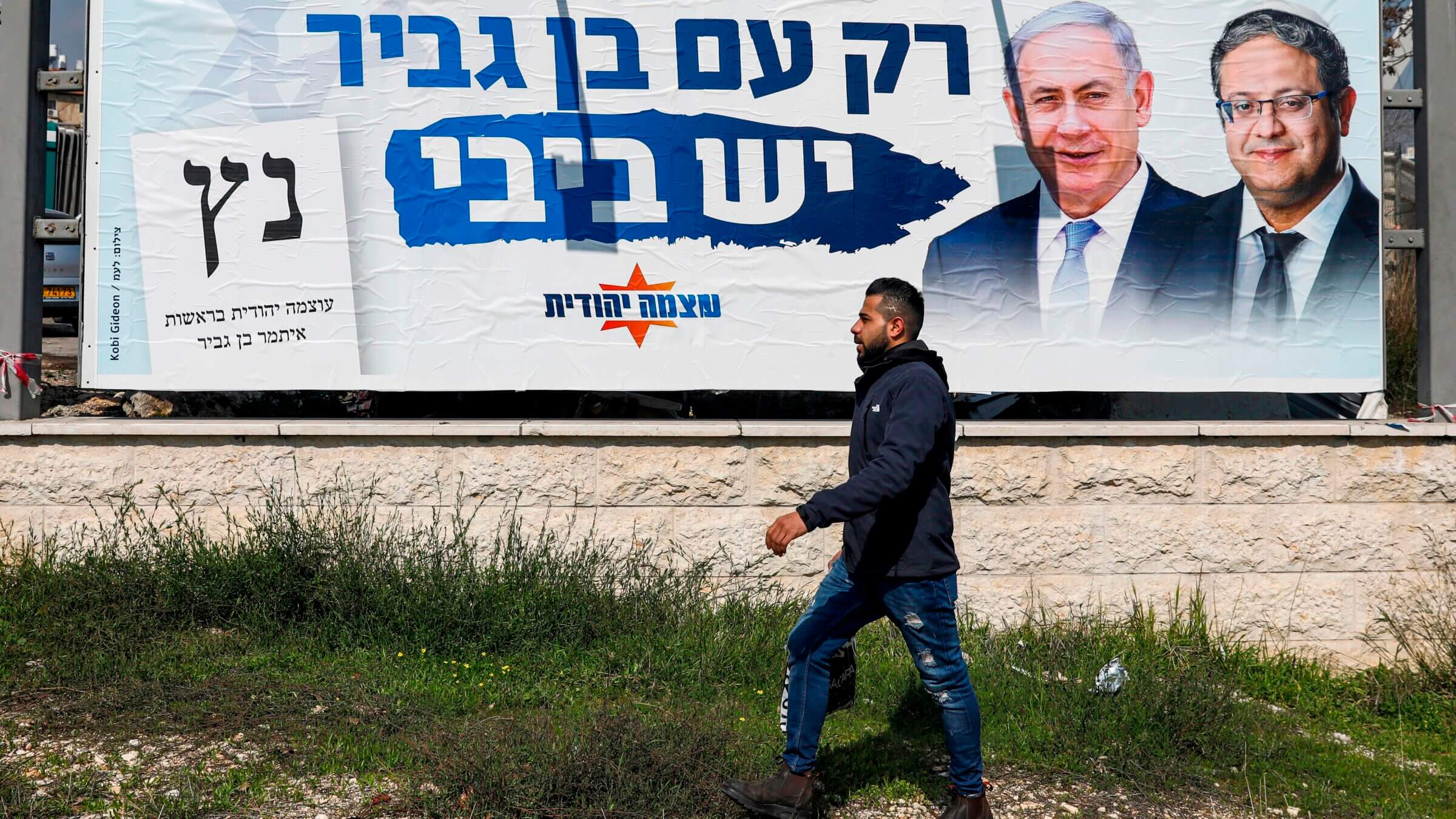 A man walks past an Otzma Yehudit party electoral campaign billboard in Jerusalem two years ago. The party's success in the recent Israeli elections has positioned it to extract demands from the new government, including possible changes to Israel’s immigration laws.