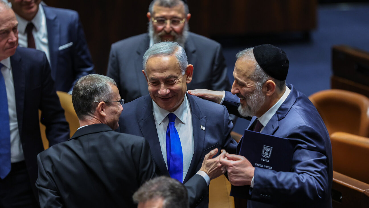 Benjamin Netanyahu, center, with Aryeh Deri, right, and other lawmakers at a plenum session on forming the government, in the Israeli parliament in Jerusalem, Dec. 29, 2022. (Yonatan Sindel/Flash90)