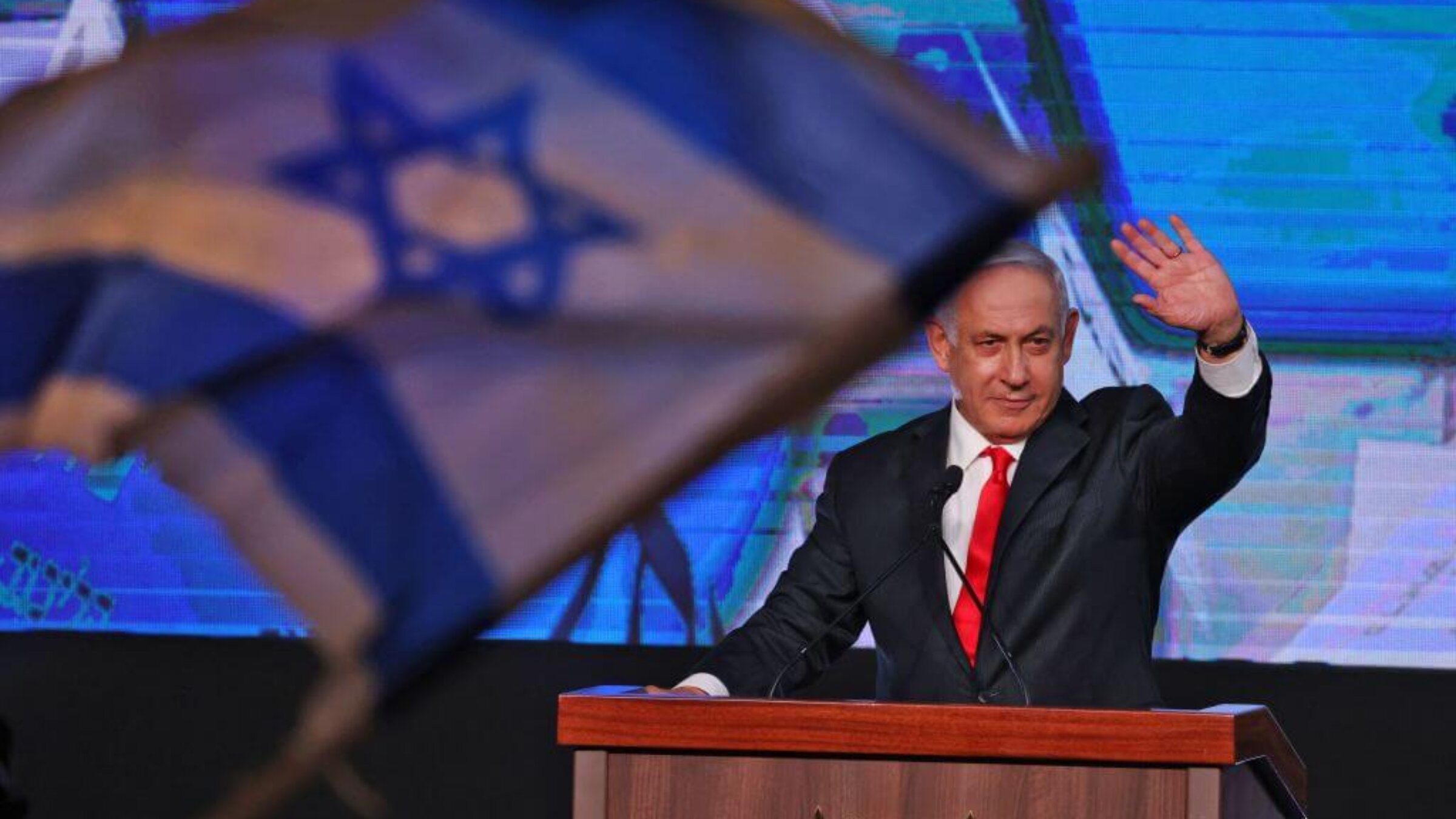 Israeli Prime Minister Benjamin Netanyahu, leader of the Likud party, waves to supporters at the party campaign headquarters in Jerusalem early on March 24, 2021.