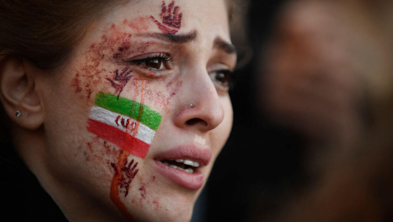 A demonstrator with an Iranian flag and red hands painted on her face attends a rally in support of Iranian protests in Paris on Oct. 9, 2022, following the death of Iranian woman Mahsa Amini.