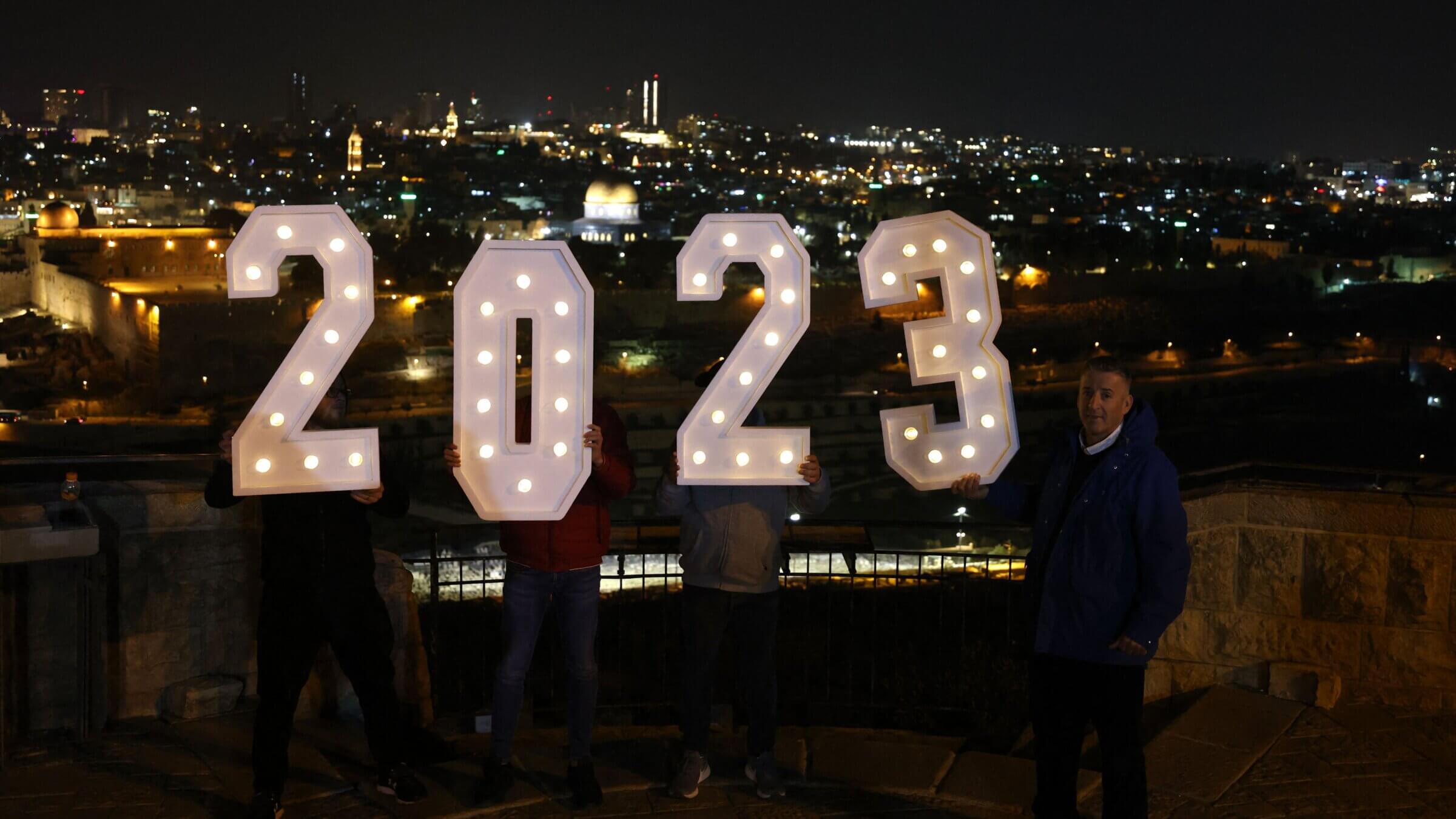 People pose for a picture with a lit up 2023 sign at the Mount of Olives in Jerusalem on Dec. 31, 2022.