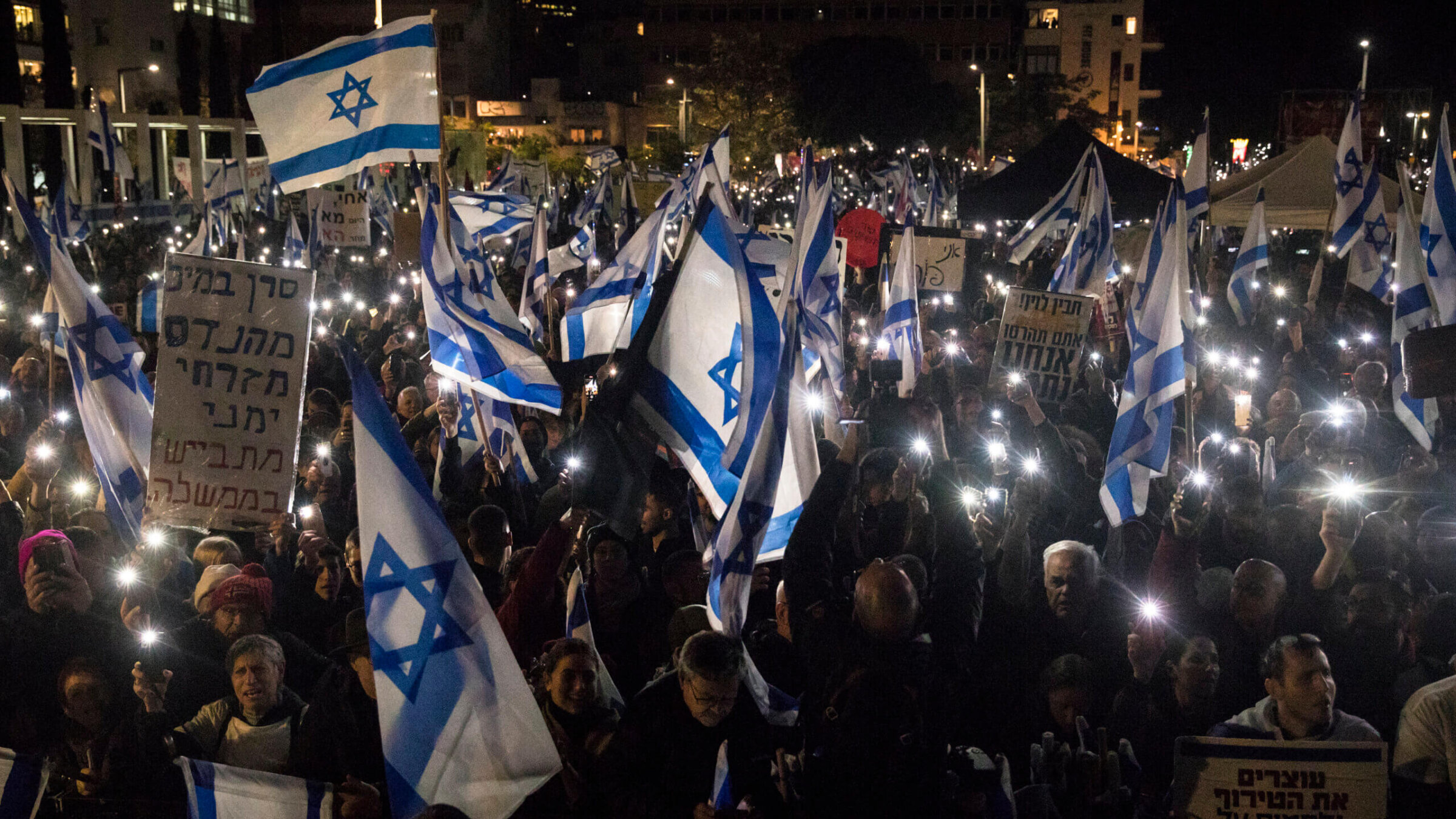 Israelis hold the Israeli flag and light their phones as they protest against the new Israeli far-right government on Jan. 14 in Tel Aviv.