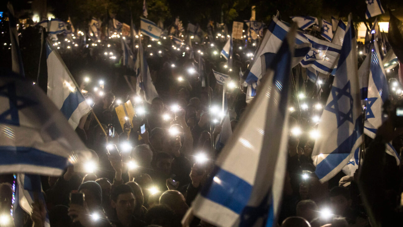 Israelis hold the Israeli flag and light their phones as they protest against the new Israeli far-right government on January 14, 2023 in Tel Aviv, Israel. 