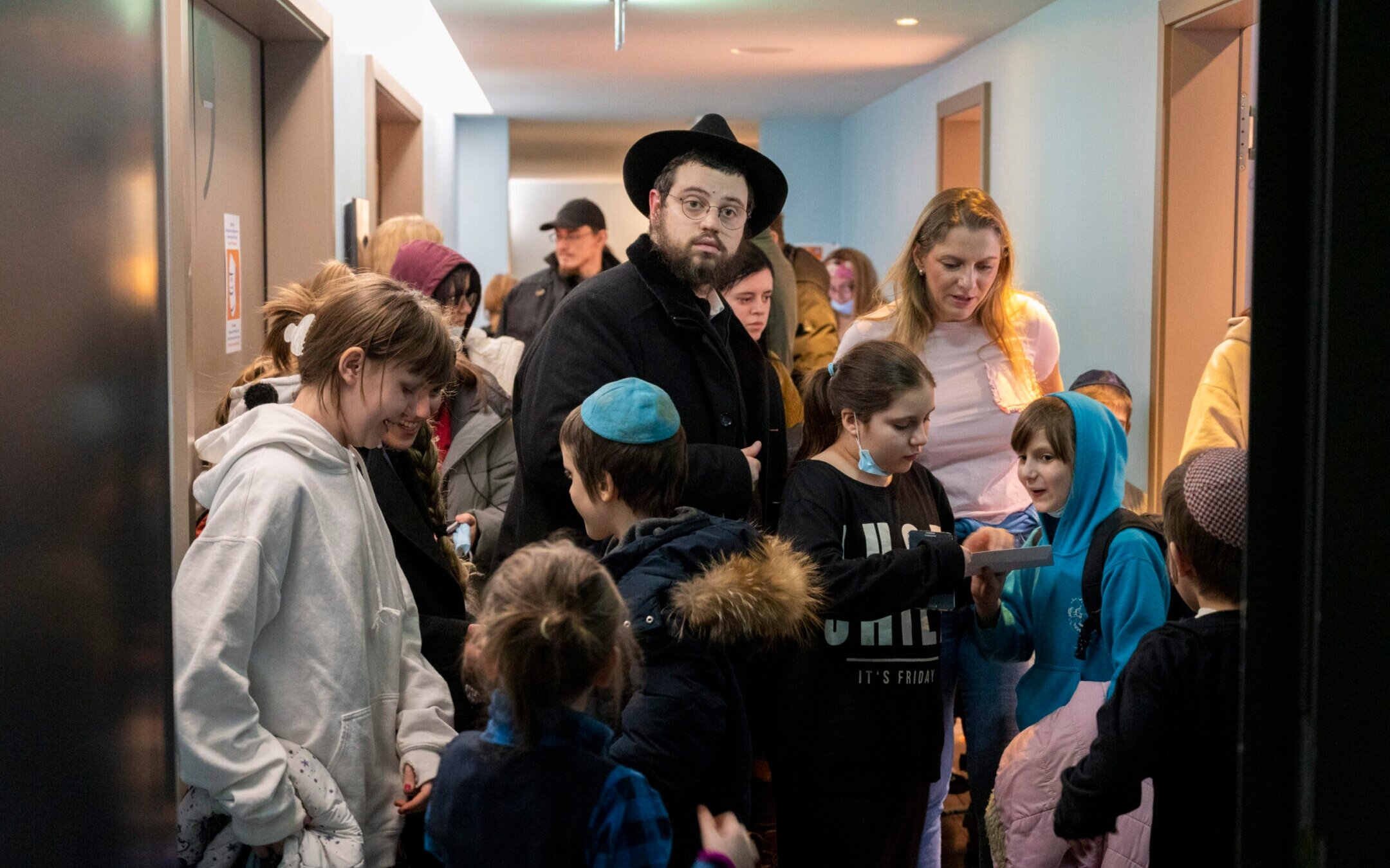 Rabbi Mendy Wolff stands in a hallway in a hotel among children he brought from a Jewish orphanage in Odessa, Ukraine. (Christophe Gateau/picture alliance via Getty Images)