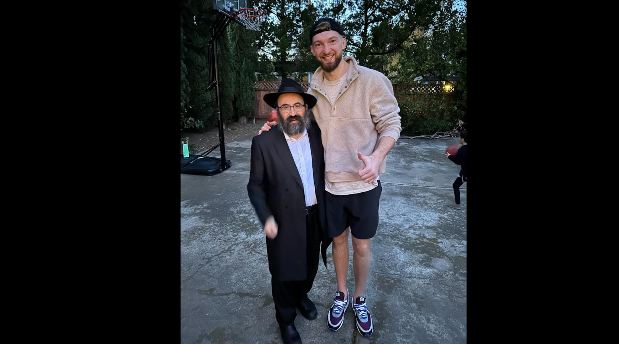 Rabbi Mendy Cohen is dwarfed by 7-foot-1 Kings center Domantas Sabonis, who attended Chabad of Sacramento’s Purim party on March 7. (Courtesy of Chabad of Sacramento)