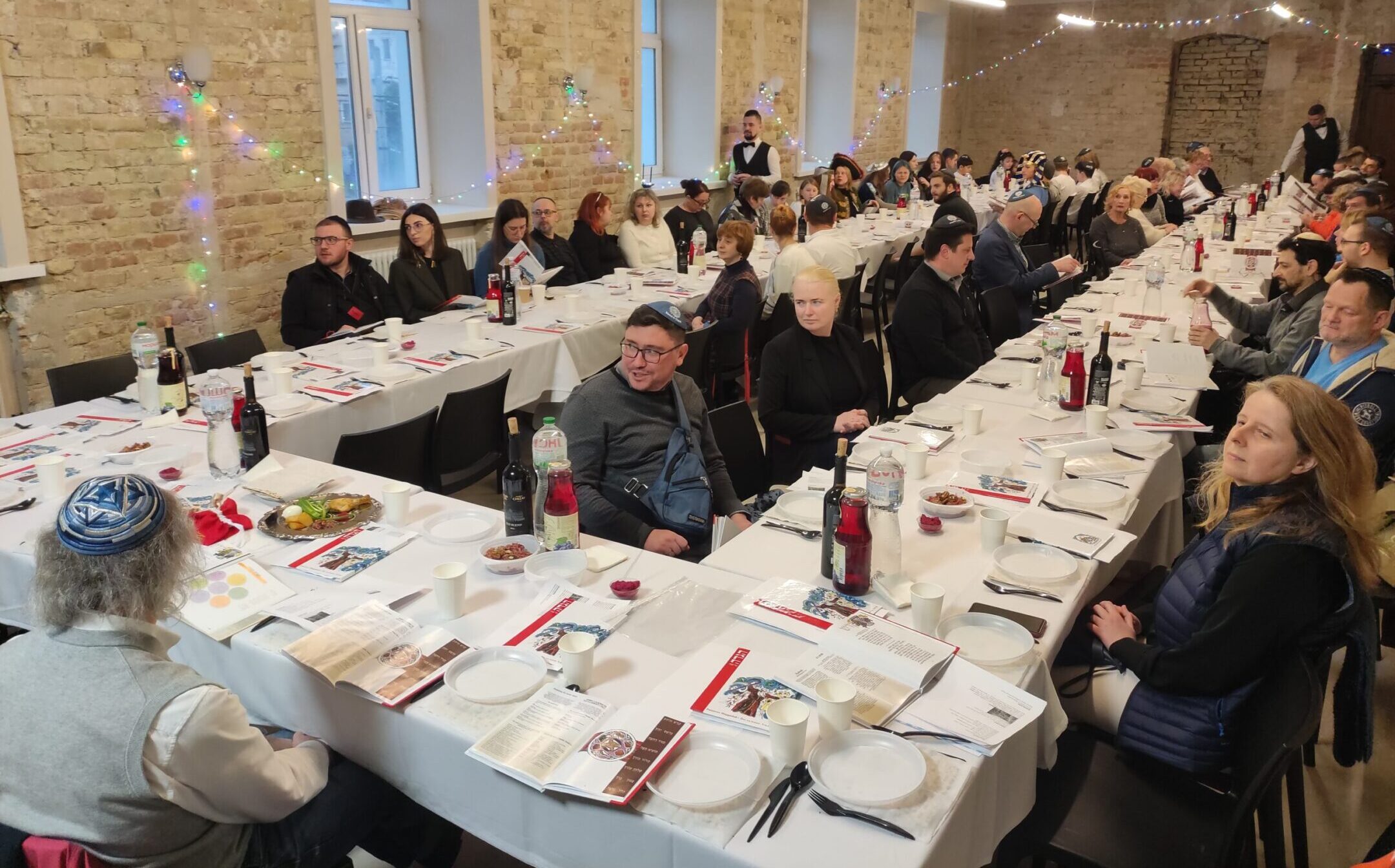 Guests at a seder in Kyiv, Ukraine, including many families from heavily damaged Kharkiv, sit around the seder table on the first night of Passover, April 5, 2023. (Marcel Gascon Barbera)