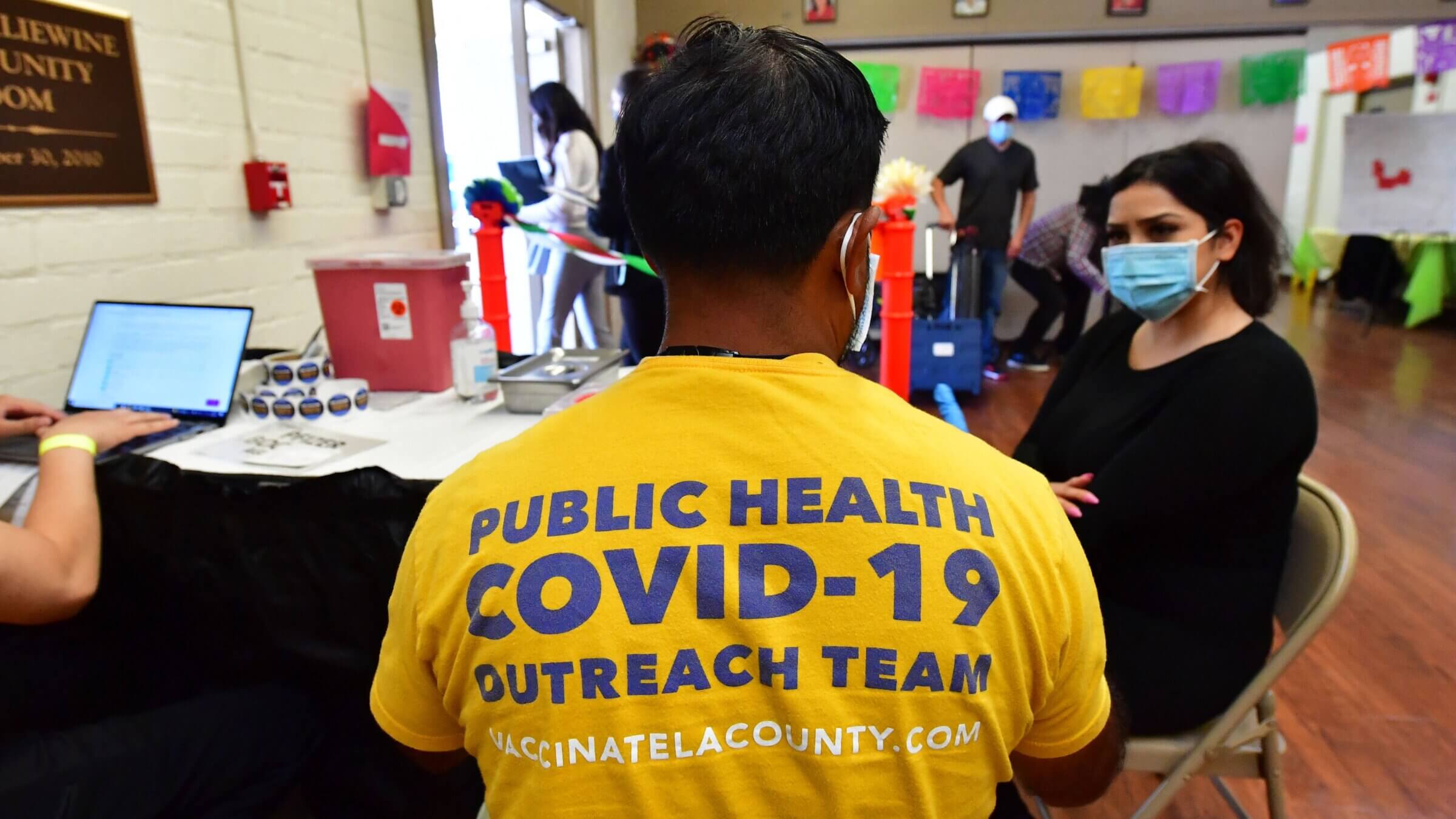 A woman points to her arm to receive her booster shot at a Covid vaccination site in Los Angeles. 