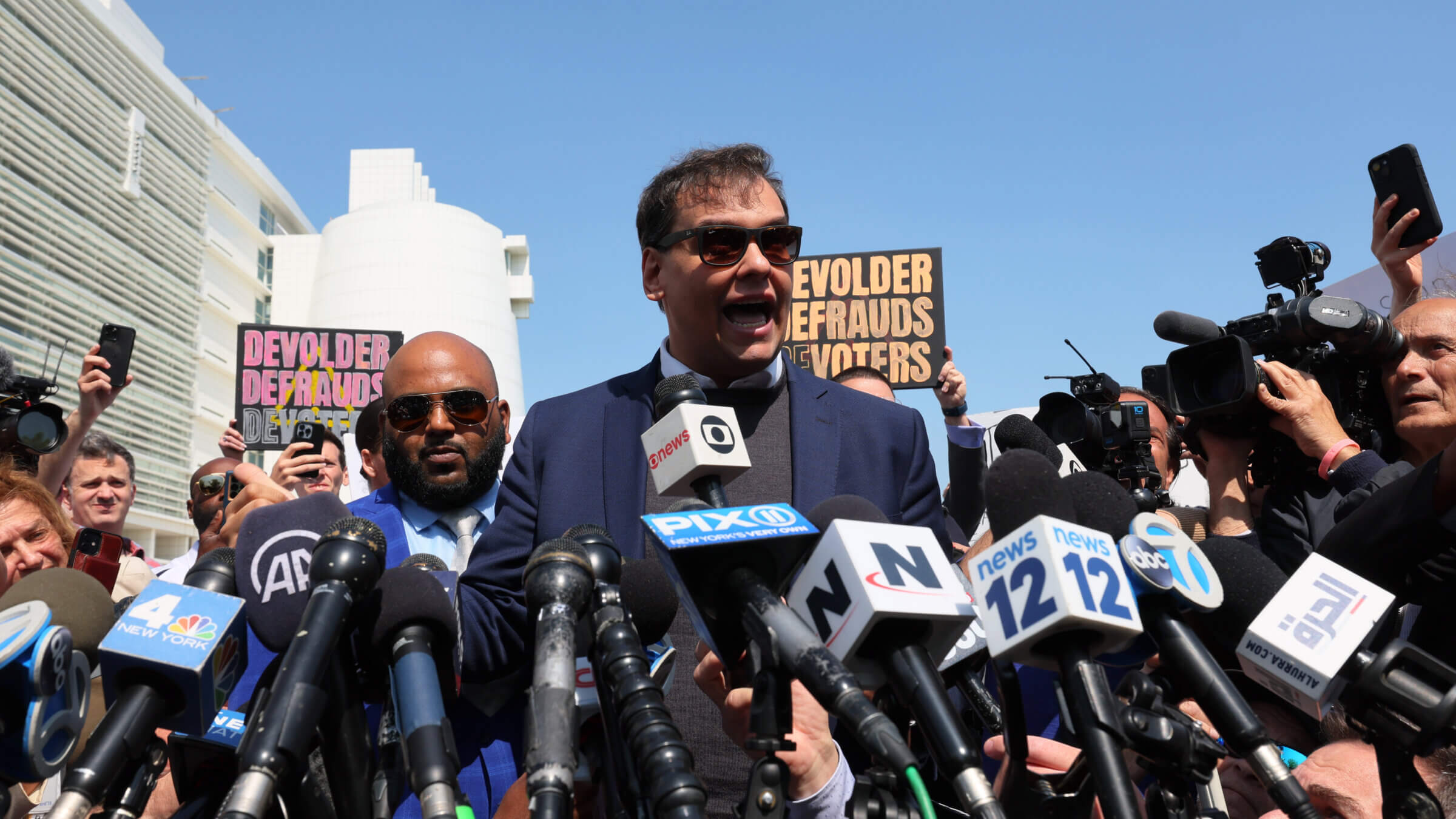 George Santos speaks to members of the press following charges from the Justice Department.