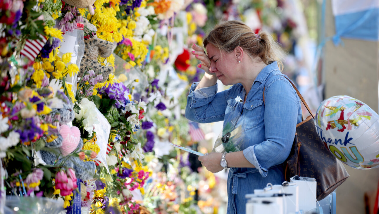 A visitor weeps as she places flowers near the memorial site for victims of the collapsed 12-story Champlain Towers South condo building on July 8, 2021, in Surfside, Florida. 