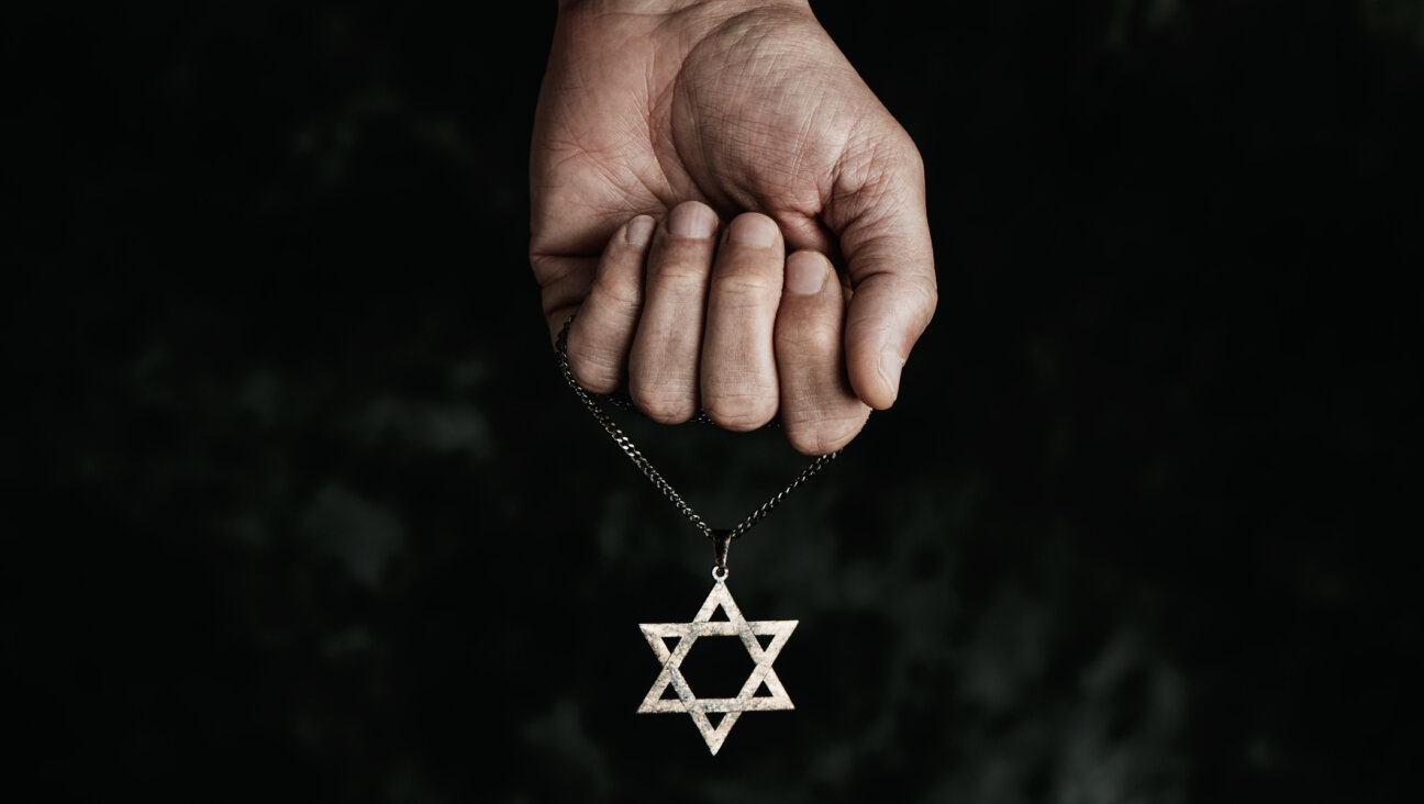 A hand holds a Star of David necklace