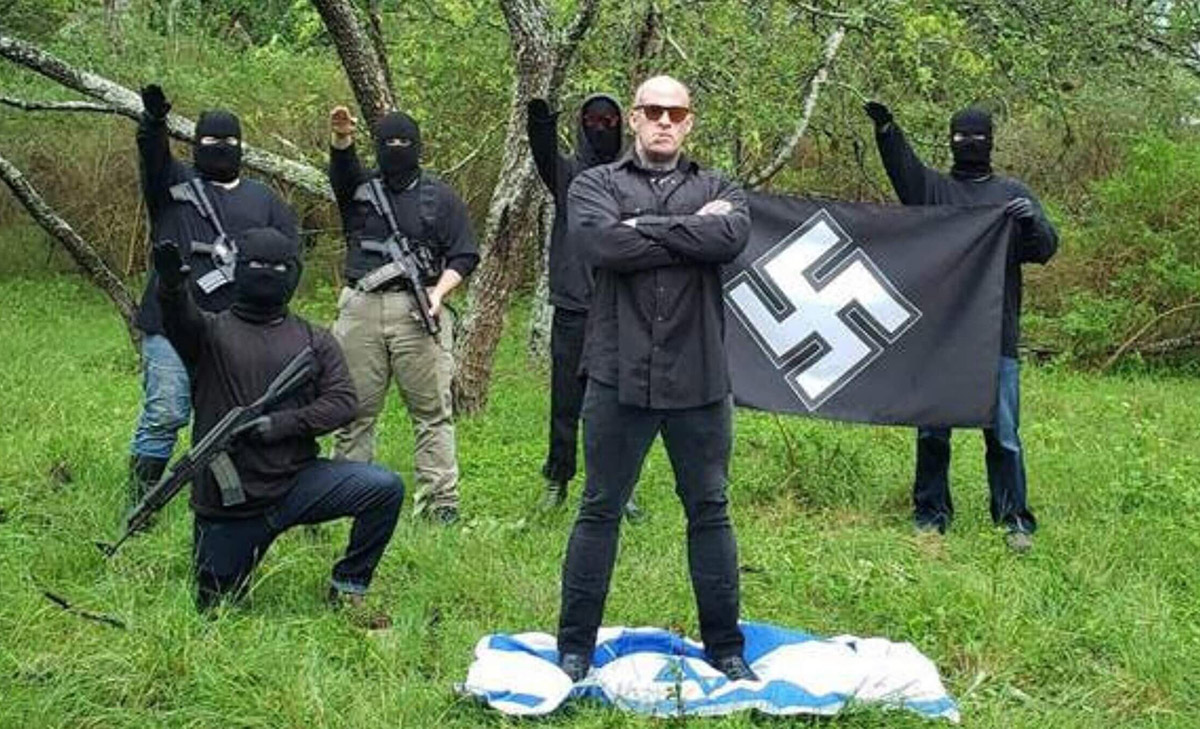 Christopher Pohlhaus stands on an Israeli flag while supporters make the Nazi salute. (Courtesy ADL)