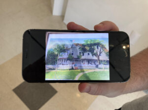 A photograph of a man's hand displaying an iPhone photo of a vintage Borscht Belt postcard