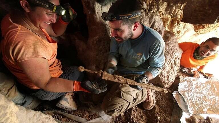 
Removing one of the swords, still in its scabbard, from the crevice where they were hidden.