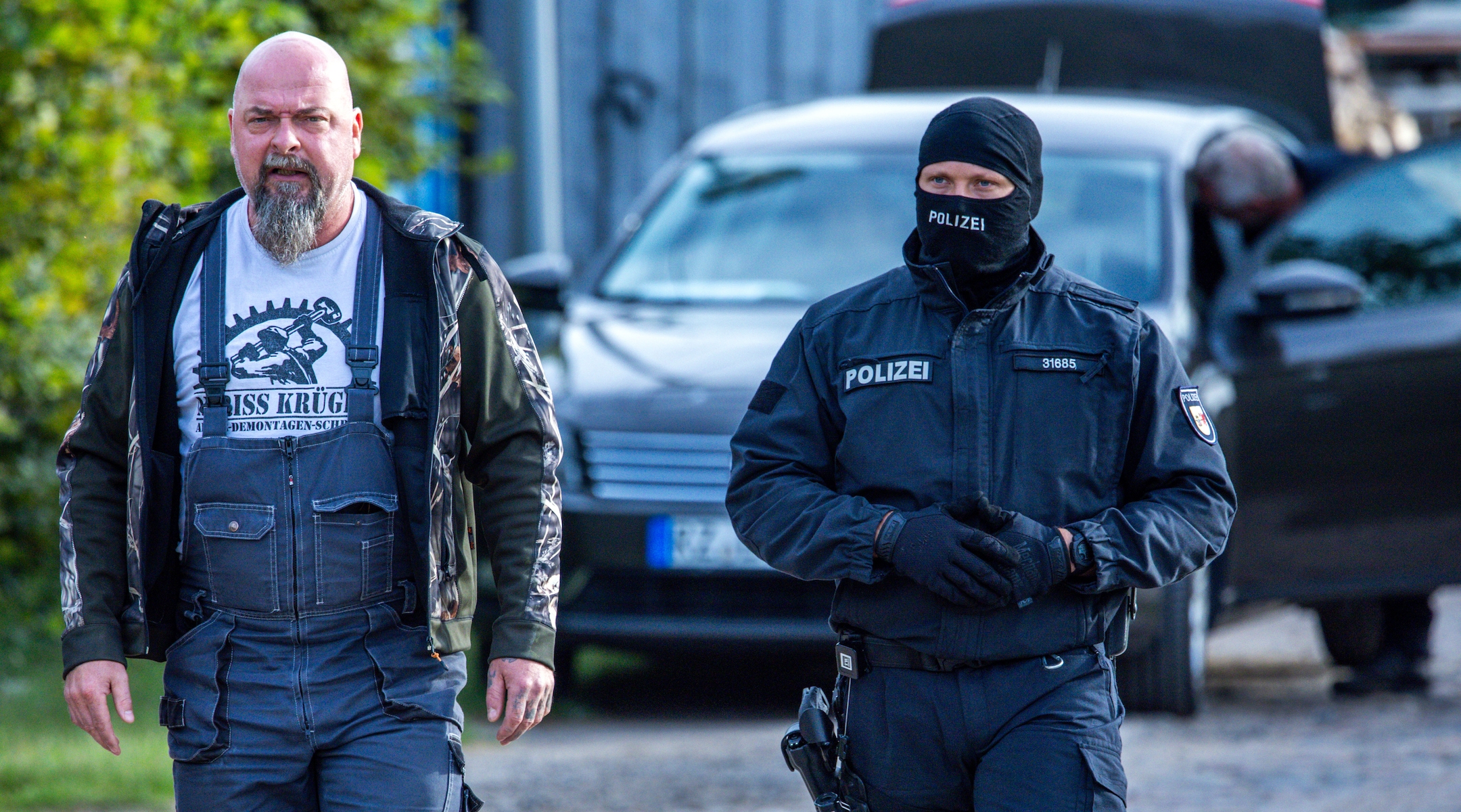 19 September 2023, Mecklenburg-Western Pomerania, Jamel: Sven Krüger (l), a right-wing extremist known throughout Germany, is accompanied by a police officer during a search operation on his property. Federal Interior Minister Faeser has banned the right-wing extremist association “Hammerskins Germany” as well as its regional offshoots and the sub-organization “Crew 38”. According to the ministry, police task forces searched the homes of 28 suspected members of the association in ten German states in the early morning. Photo: Jens Büttner/dpa (Photo by Jens Büttner/picture alliance via Getty Images)