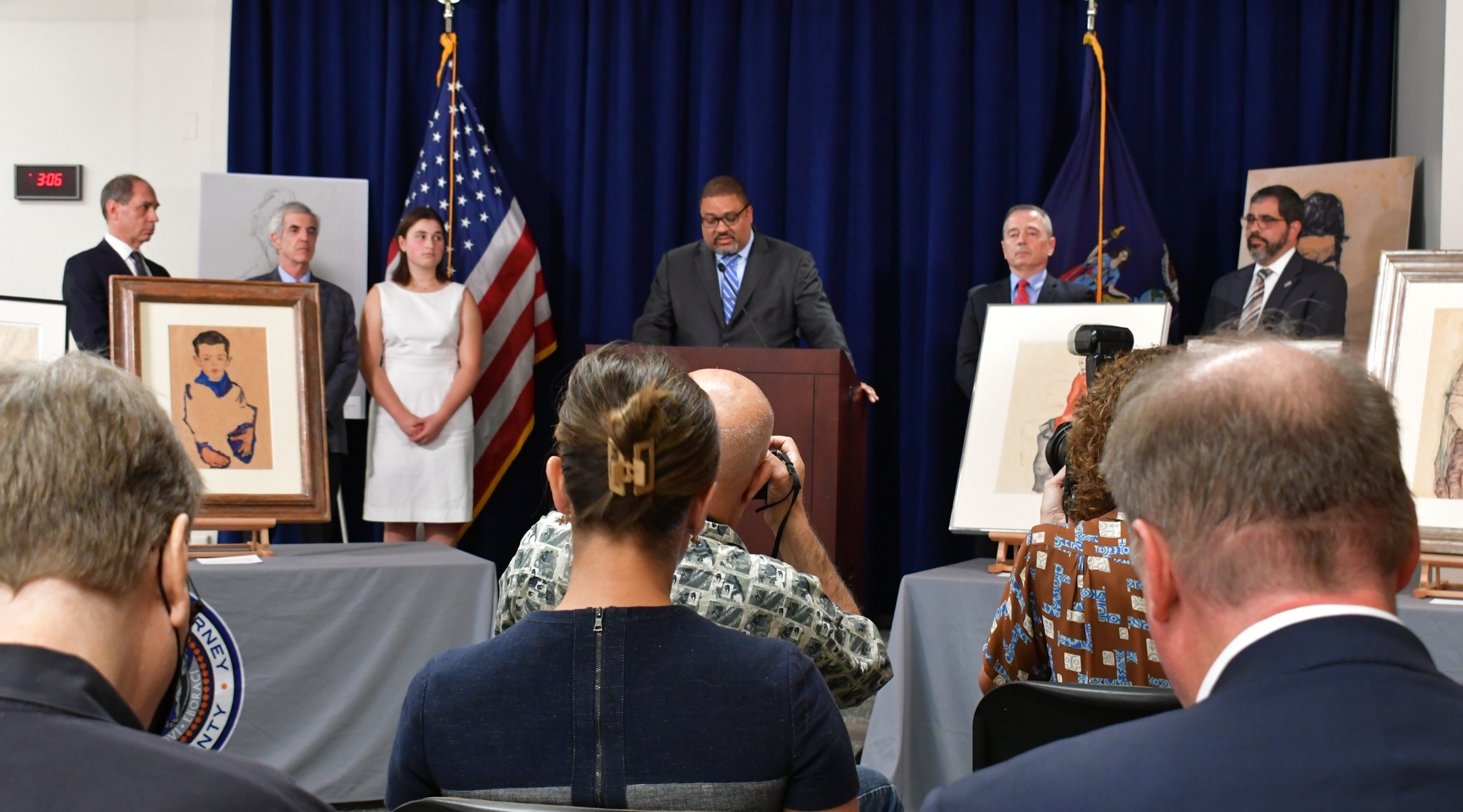 Manhattan district attorney Alvin Bragg, center, delivers remarks during a Sep. 20, 2023 ceremony to return stolen artworks to the heirs of Fritz Grünbaum’s estate: Timothy Reif, David Frankel, and Sarah Reif, left, pictured left to right. (Jackie Hajdenberg)