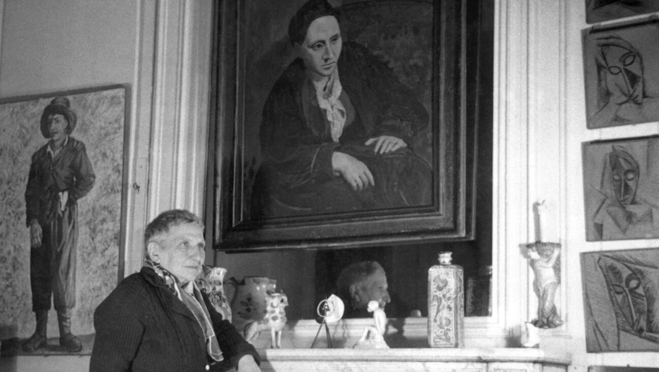 Gertrude Stein poses in front of the portrait of her that Picasso painted in 1906.