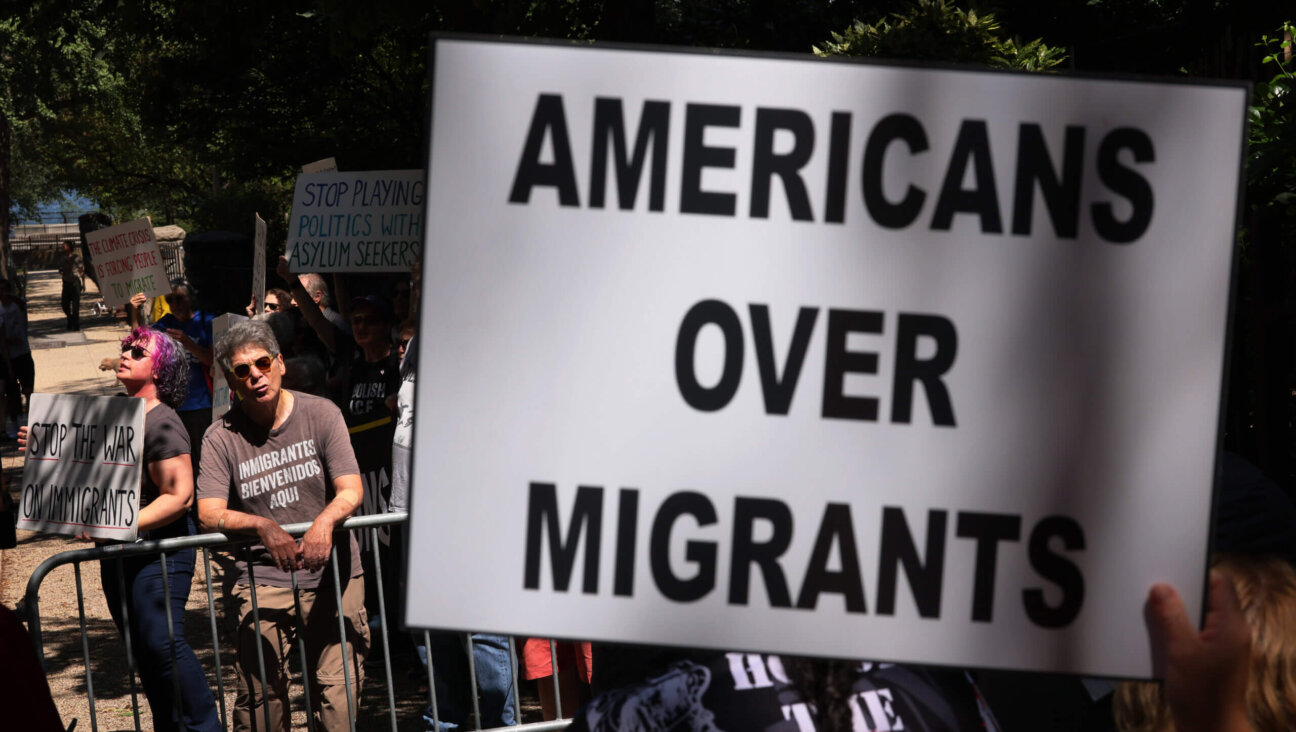 Counter protestors hold up signs as people participate in an anti-migrant rally and protest outside of Gracie Mansion on August 27, 2023 in New York City. 