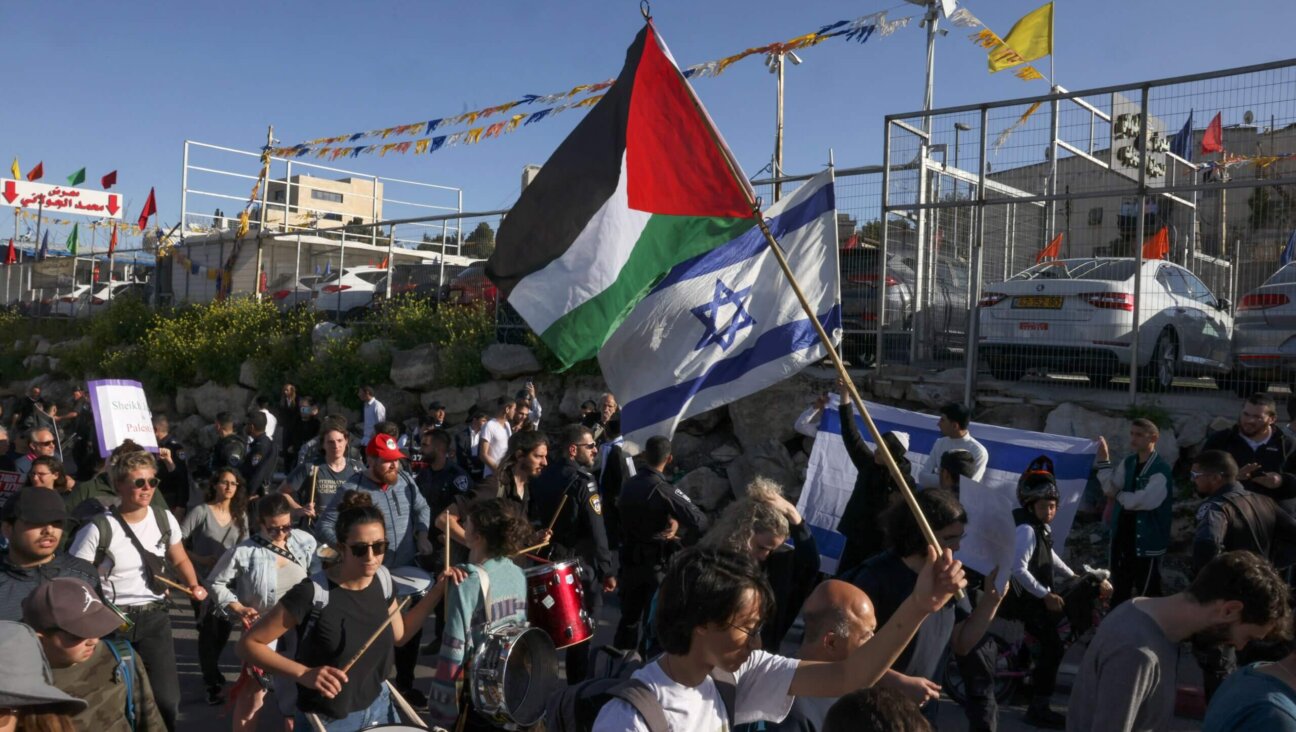 Israeli settlers lift national flags during a protest by left-wing Israeli activists and Palestinians waving Palestinian flags and banners against Israeli occupation and settlement activity in the neighbourhood of Sheikh Jarrah in Israeli-annexed East Jerusalem, on March 17, 2023. 