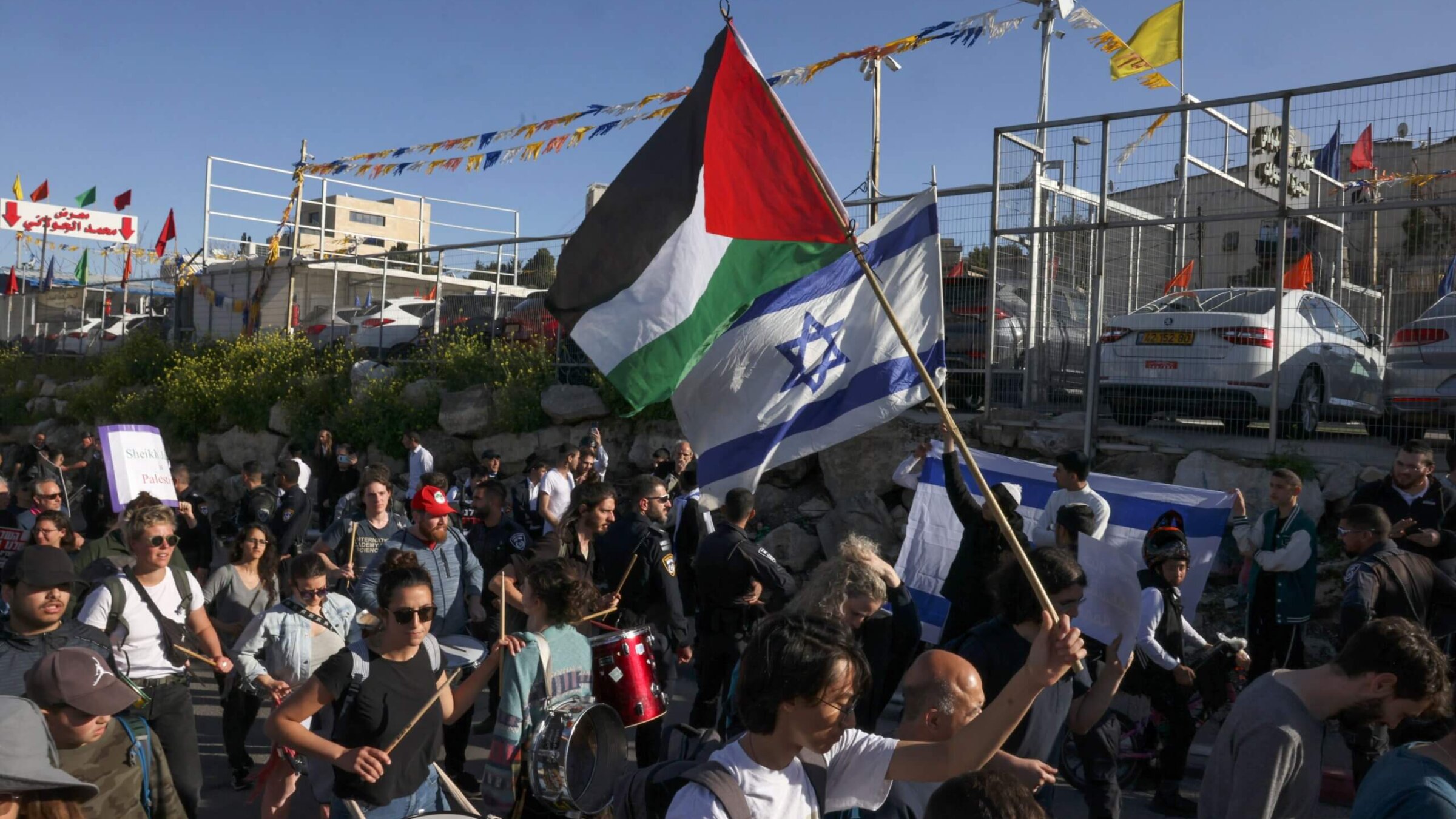 Israeli settlers lift national flags during a protest by left-wing Israeli activists and Palestinians waving Palestinian flags and banners against Israeli occupation and settlement activity in the neighbourhood of Sheikh Jarrah in Israeli-annexed East Jerusalem, on March 17, 2023. 