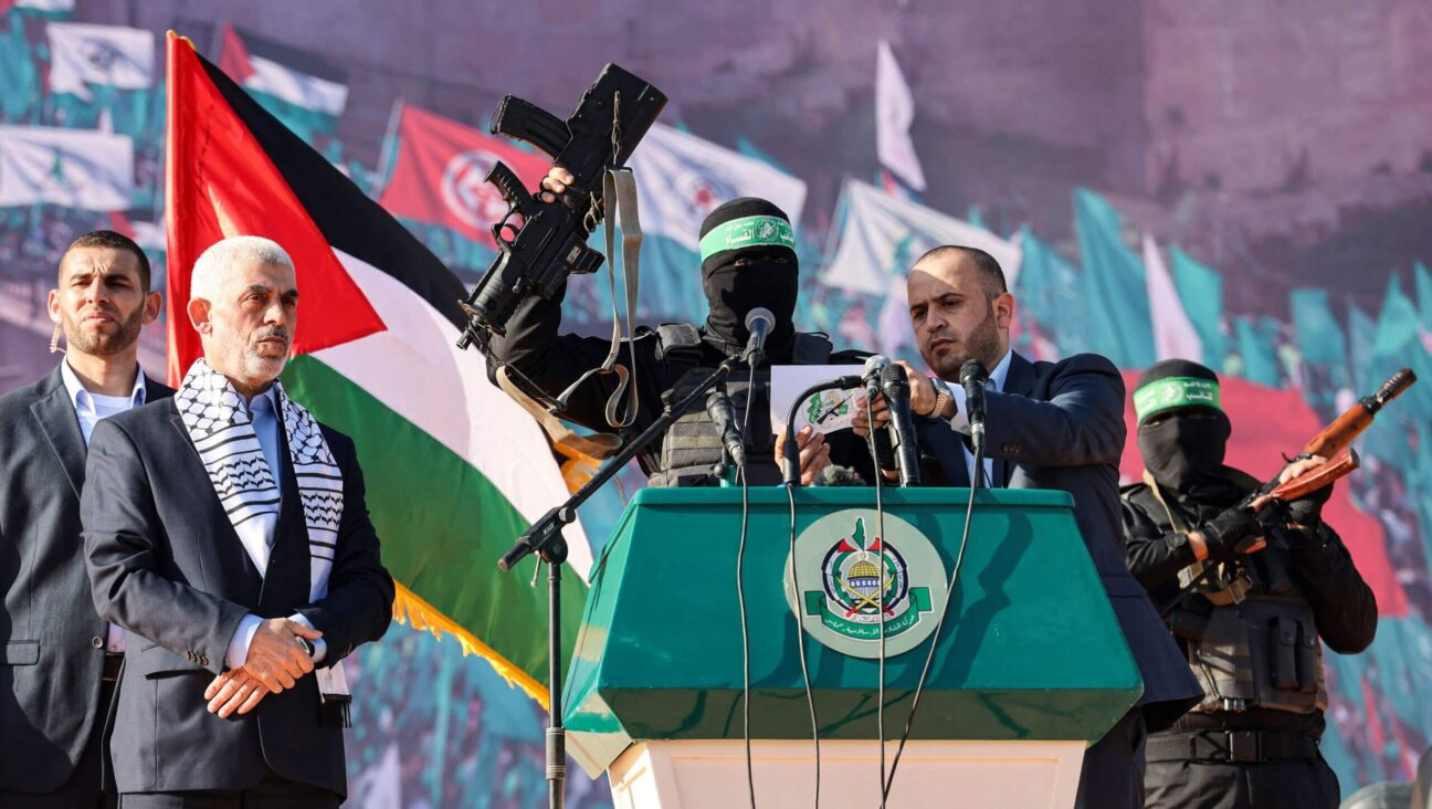 Yahia al-Sinwar, <i>second from left</i>, the current Hamas leader, stands by as a masked Hamas fighter holds up a firearm that reportedly belonged to Israeli soldier Hadar Goldin — whose body is believed to have been held by Hamas since 2014 — during a 2022 rally marking the 35th anniversary of the terrorist group's foundation.