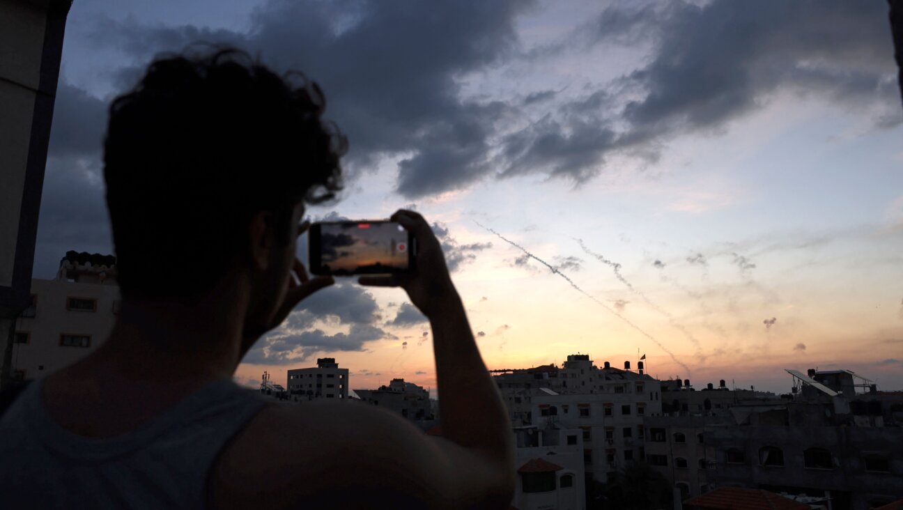 A man records a video with his mobile phone of rockets being fired from Gaza City towards Israel.