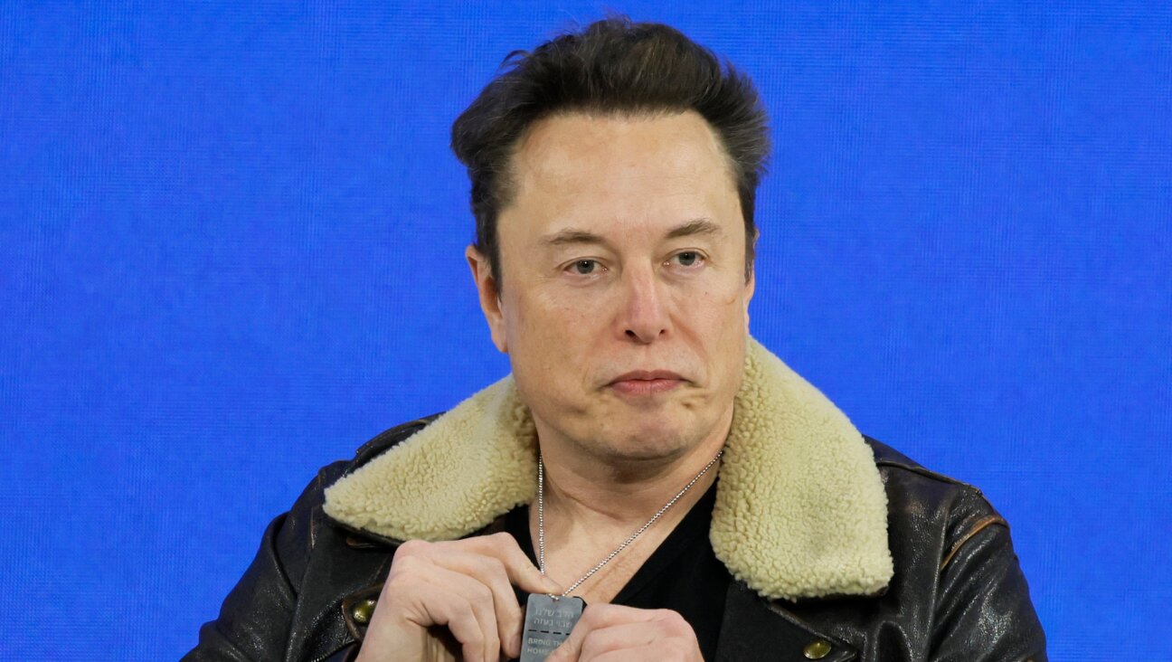 Elon Musk holds up a pendant from Israel that says “Bring Them Home” as he speaks during the New York Times annual DealBook summit on November 29, 2023 in New York City. (Michael M. Santiago/Getty Images)