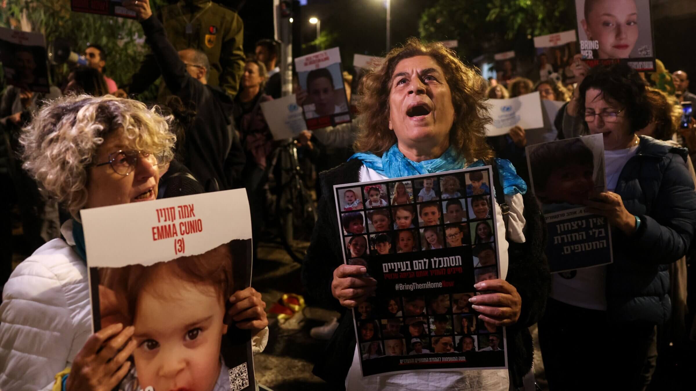 A woman holds a portrait of hostage Emma Cunio, 3 years old, as protesters lift placards during a rally outside the UNICEF offices in Tel Aviv on Nov. 20