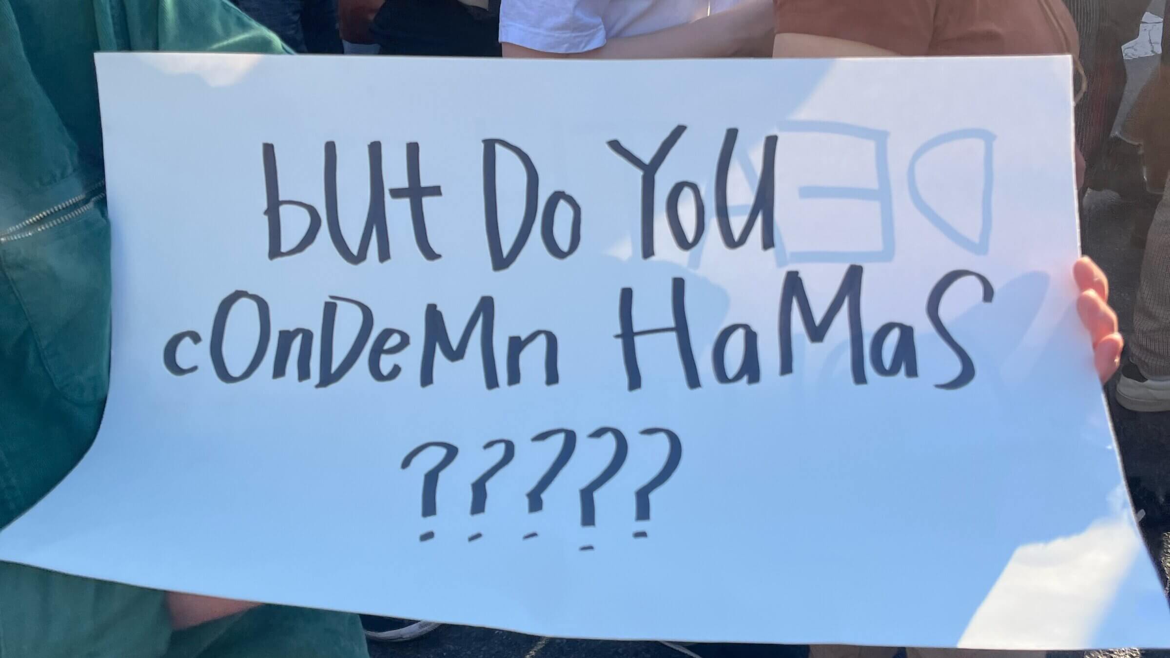 At a pro-Palestine march, a woman carries a sign asking, 'But do you condemn Hamas?'