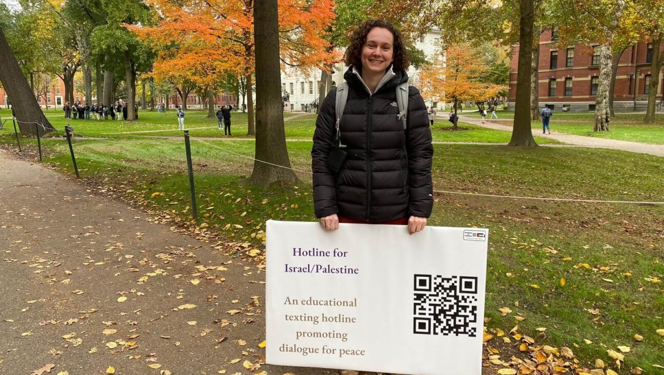 Shira Hoffer in Harvard Yard with a sign for her hotline providing resources and information about the Israeli-Palestinian conflict.