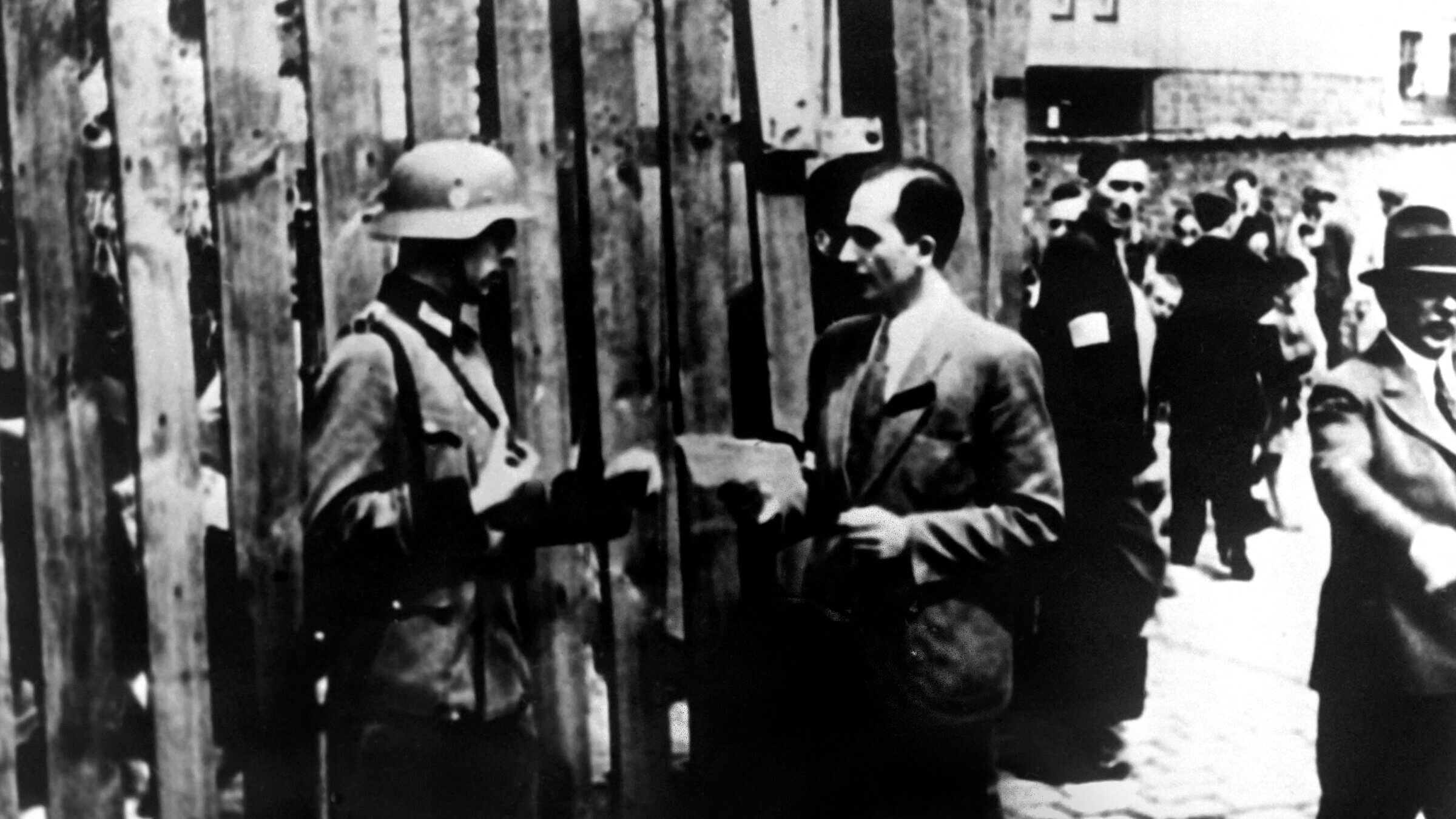 In 1943, a Nazi soldier checks someone's ID in the Warsaw Ghetto.