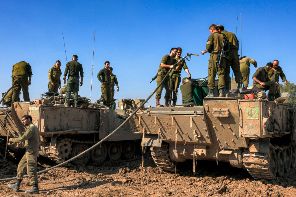 Israeli soldiers refuel an armored vehicle near the border with the Gaza Strip in southern Israel on December 19, 2023.