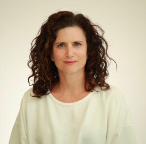 Rachel Fishman Feddersen, a white woman, smiling gently, wearing a white shirt in a professional photograph.