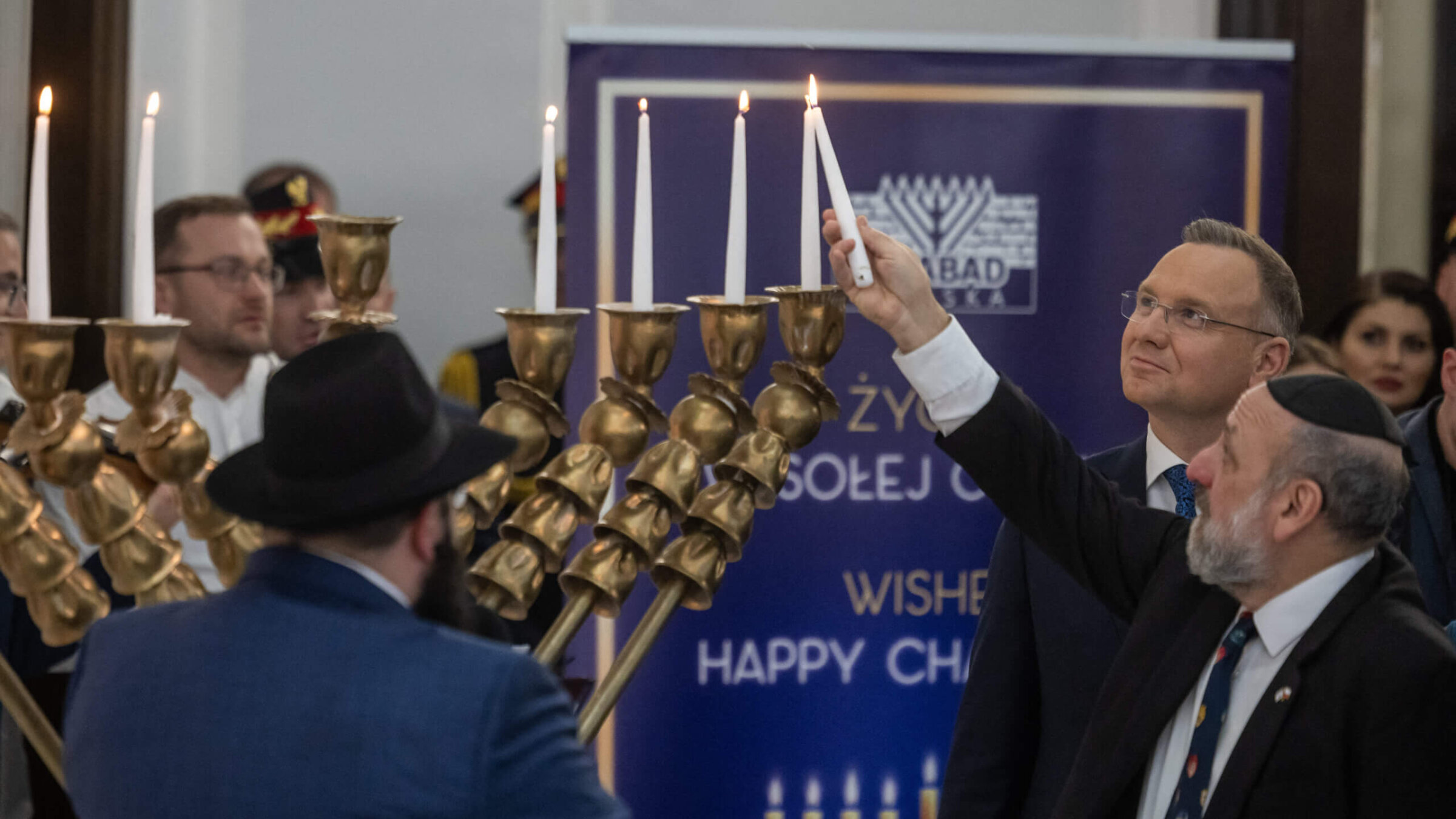 Polish President Andrzej Duda, <i>second from right</i>, looks on as Chief Rabbi of Poland Michael Schudrich, <i>right</i>, kindles the Hanukkah menorah in the Polish Parliament in Warsaw, on Dec. 14 — a day after far-right lawmaker Grzegorz Braun used a fire extinguisher to put out the candles.