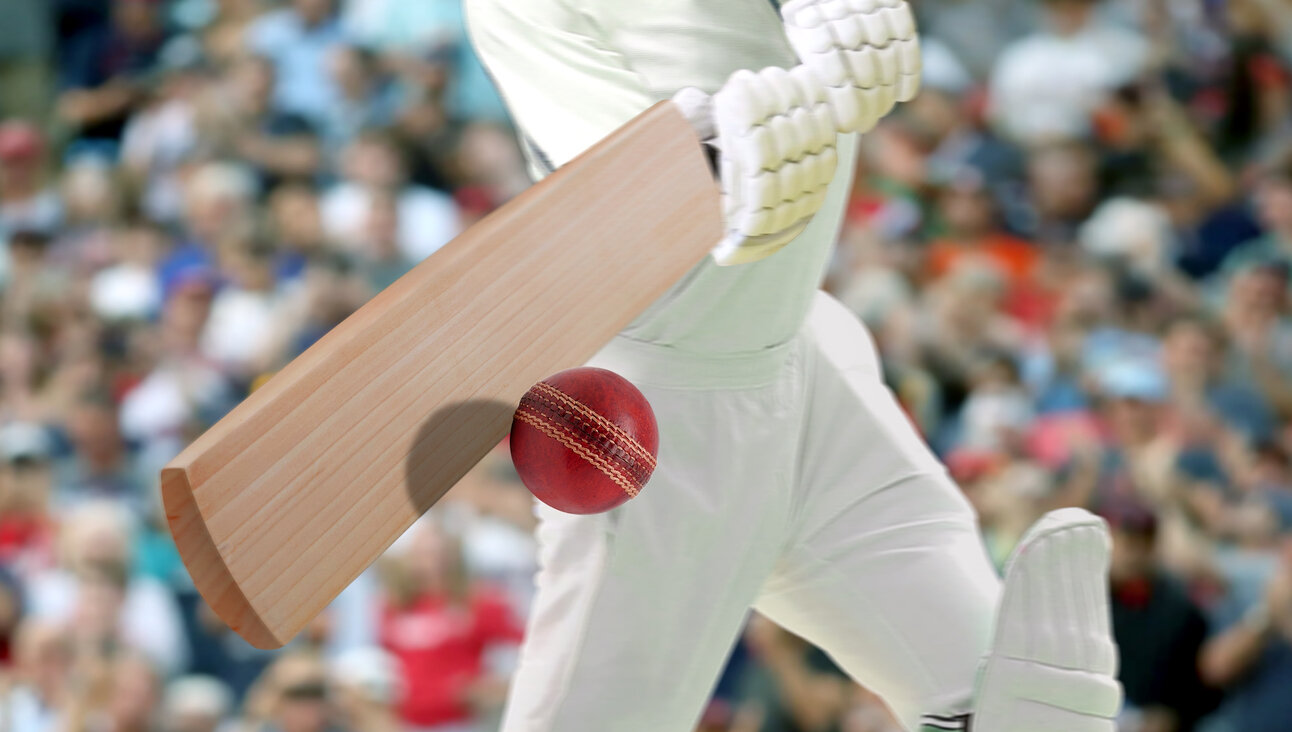 A cricket player hitting the ball in a stadium.