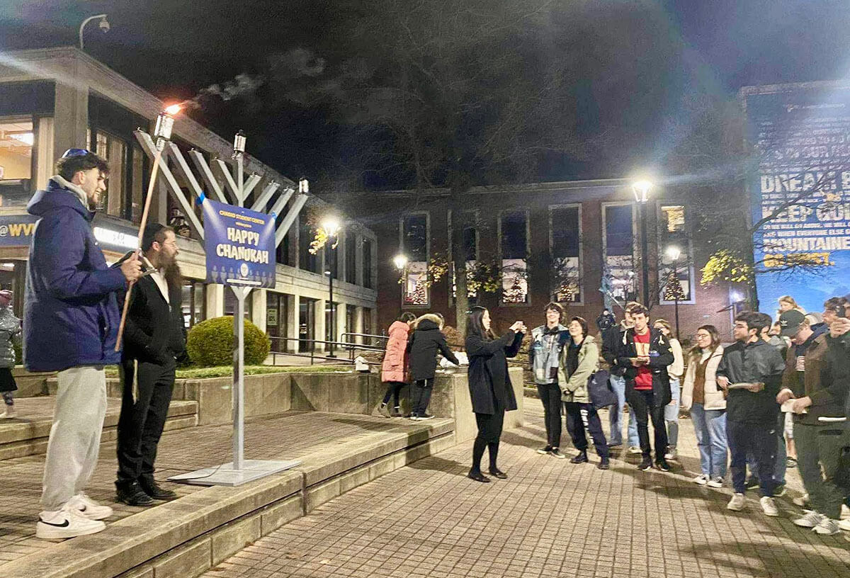 WVU basketball player Ofri Naveh, far left, lights the menorah on the campus of West Virginia University on the first night of Hanukkah, 2023.