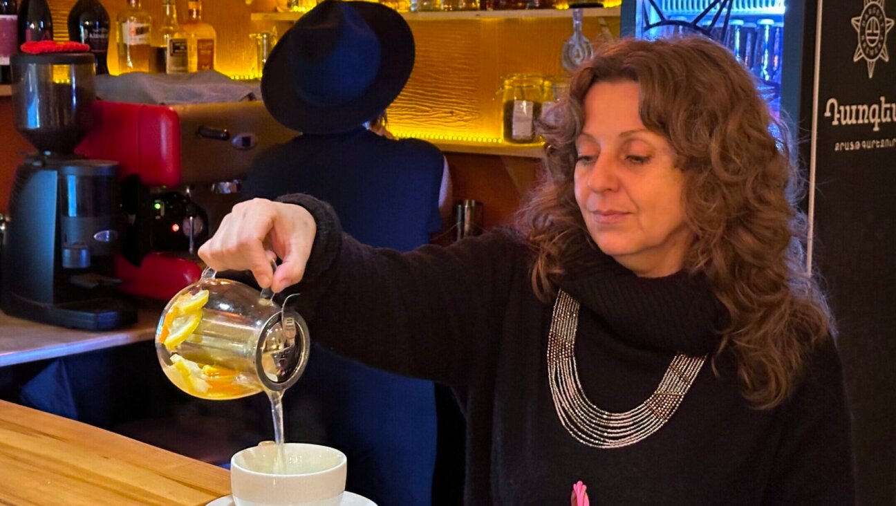 Julia Kislev, a Crimean Jew who’s been living in Armenia since 2016, pours a cup of tea at Mama Jan, the café she owns in Yerevan. Mama Jan has become the unofficial gathering place for Russian Jews who have settled here since Russia invaded Ukraine two years ago. (Larry Luxner)