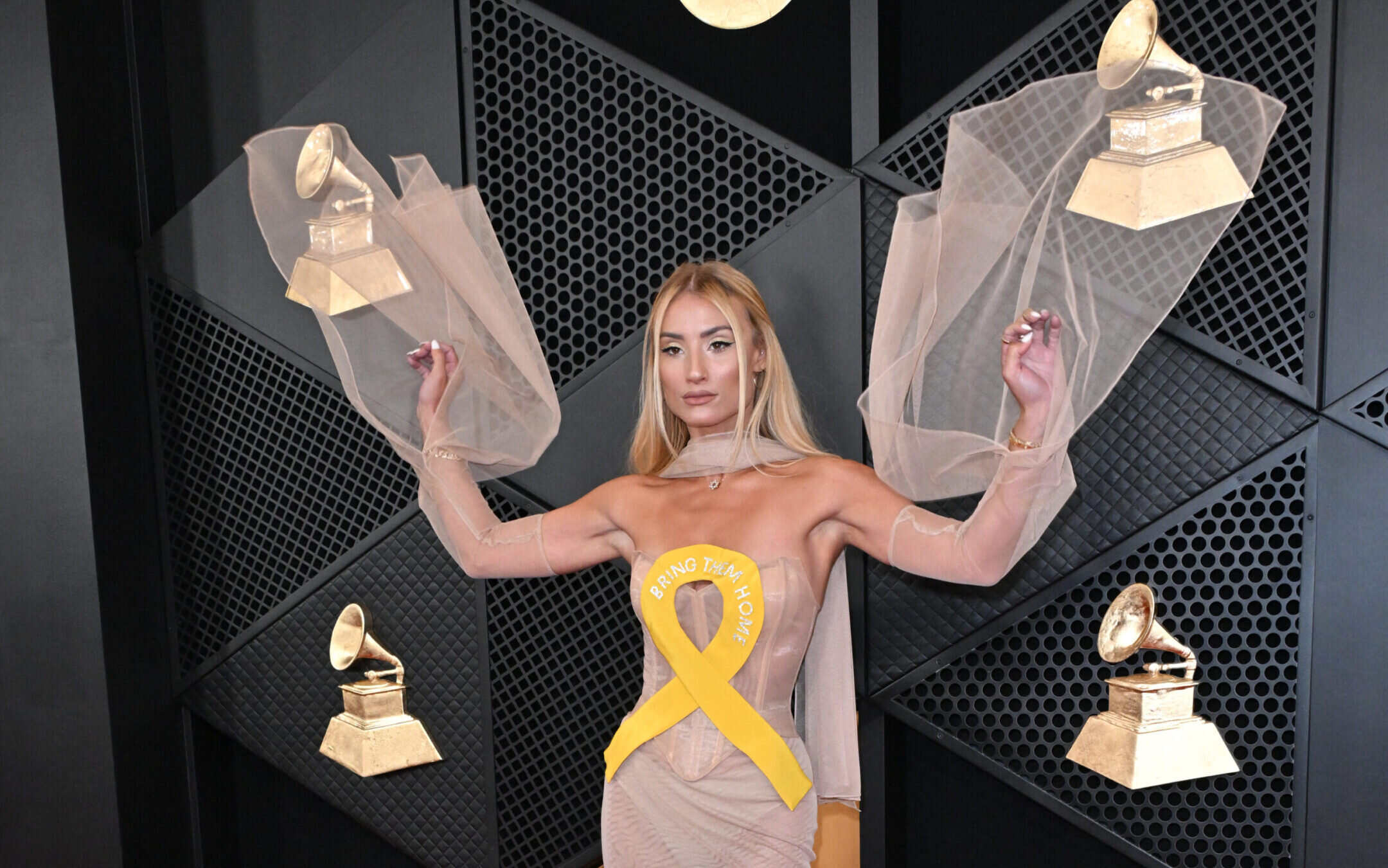 Singer and influencer Montana Tucker arrives for the Grammys wearing a dress with a yellow ribbon meant to call attention to the Israeli hostages in Gaza.