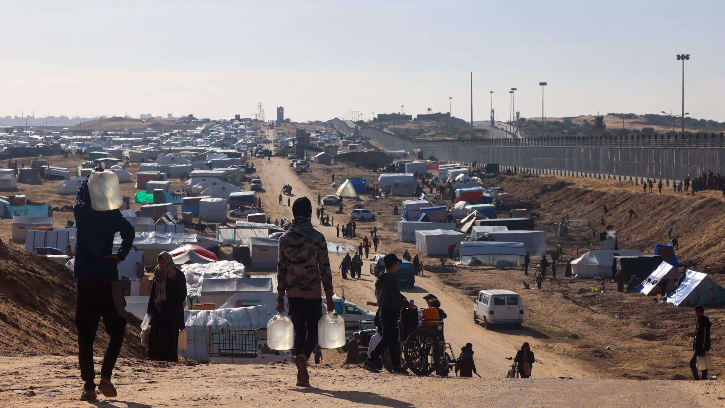 People ferry water at a makeshift tent camp for displaced Palestinians in Rafah near the border with Egypt in the southern Gaza Strip.