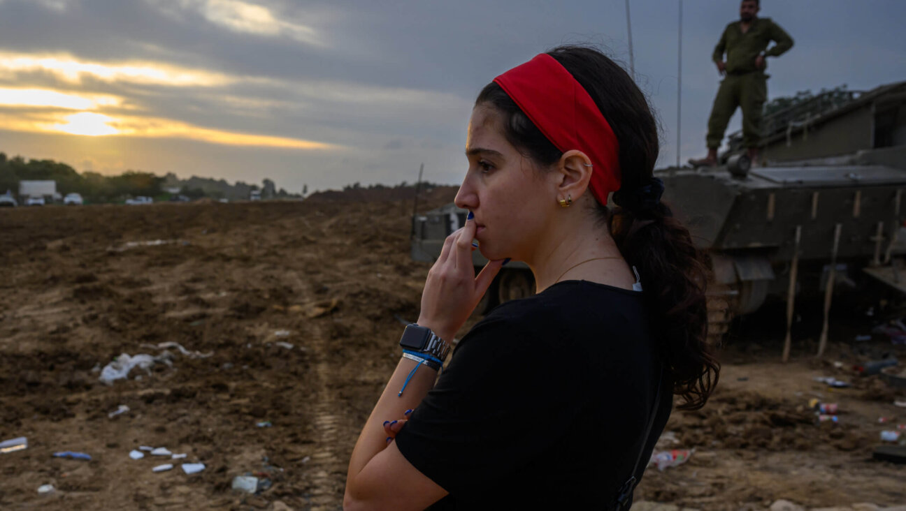 A woman watches as IDF forces arrive to a staging area in the Gaza Envelope for the first time since the Hamas attack,  Dec. 17,  in Southern Israel. 